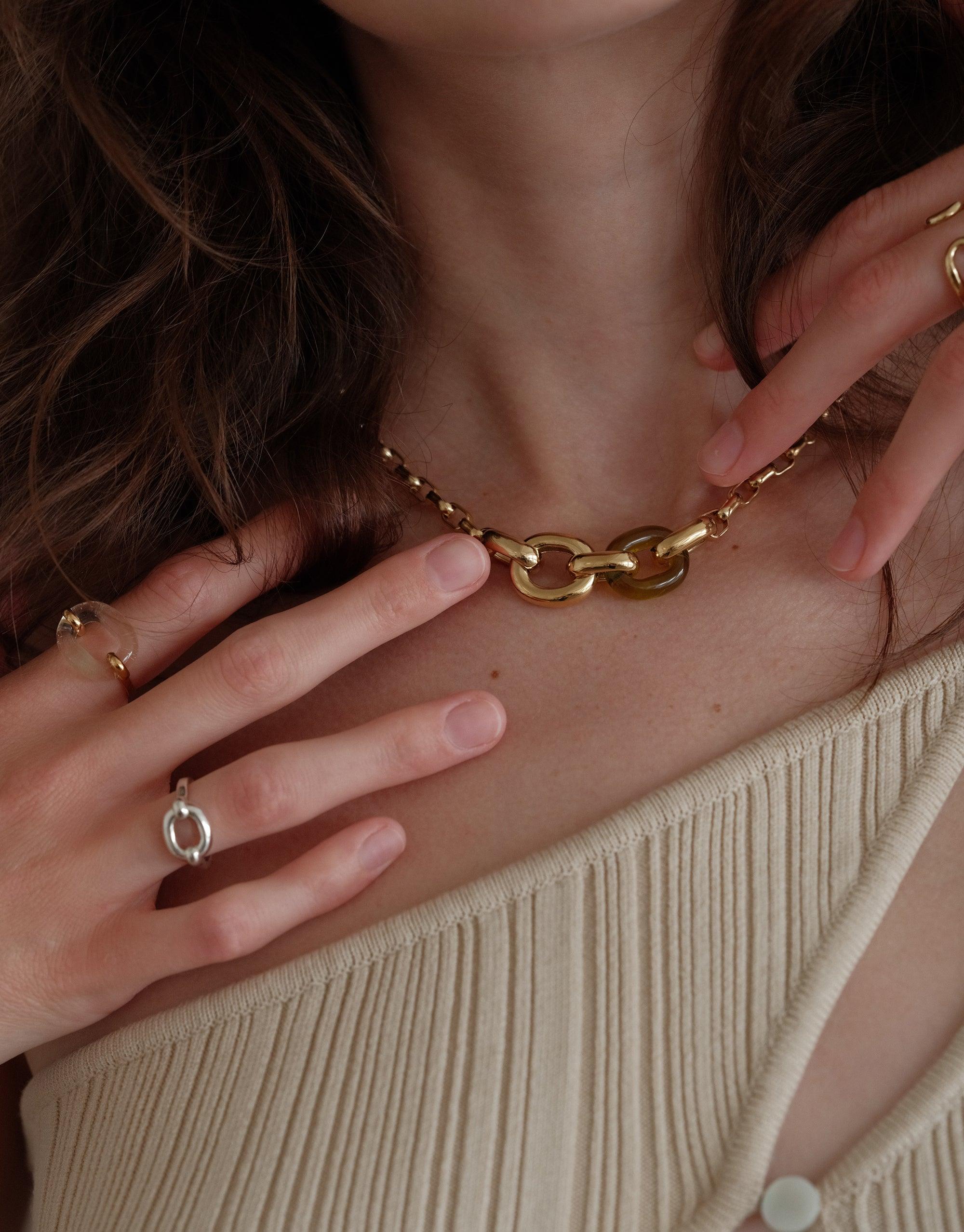 Elegant gold chain necklace with interlocking loops worn by model, complemented by delicate rings including the Core Loop Ring | Small. Showcasing sustainable jewelry design that symbolizes unity and connection. CLED