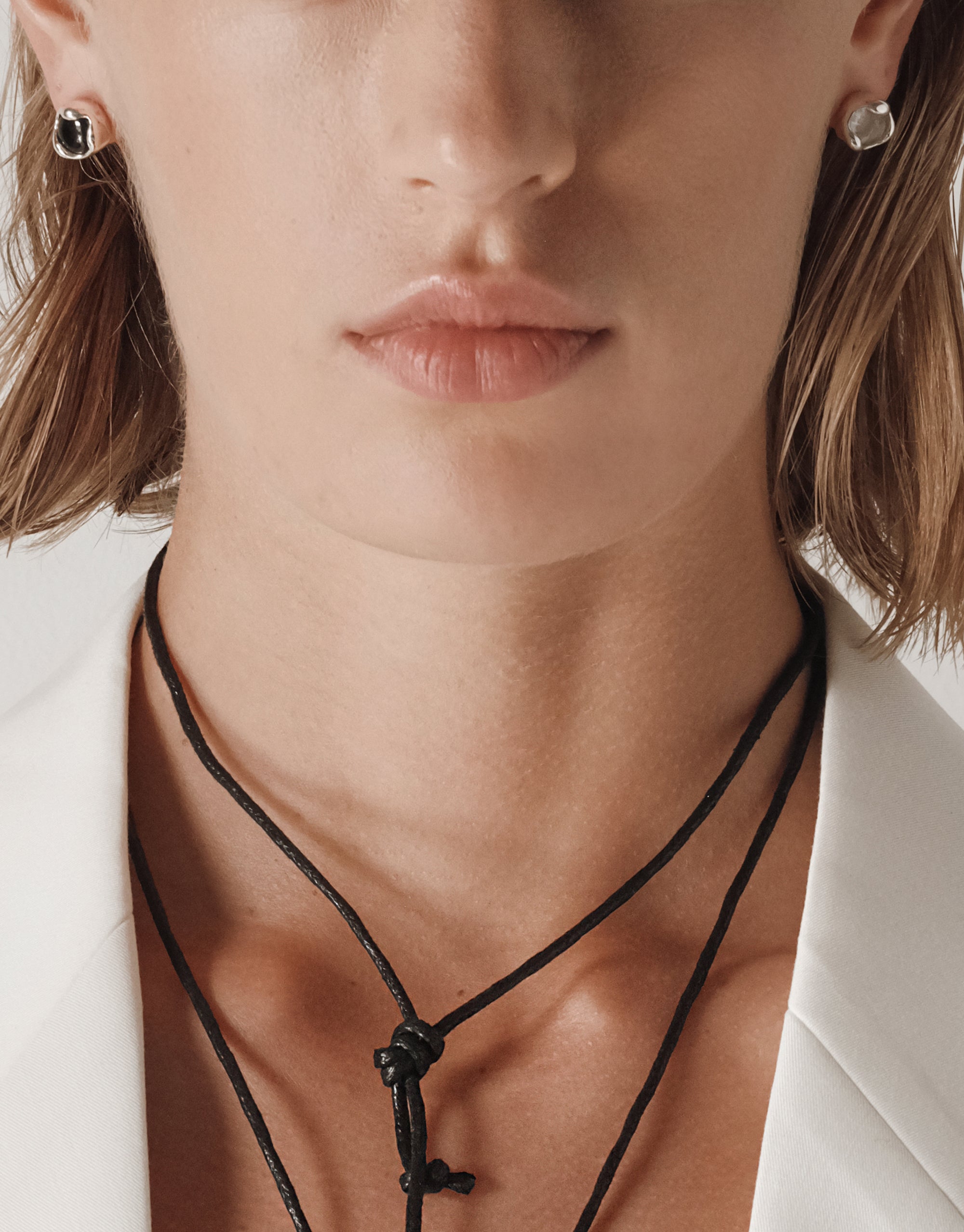 Eco-friendly Orb Stud Earrings with silver bezel settings and clear cabochon stones shown on model wearing white blazer - CLED