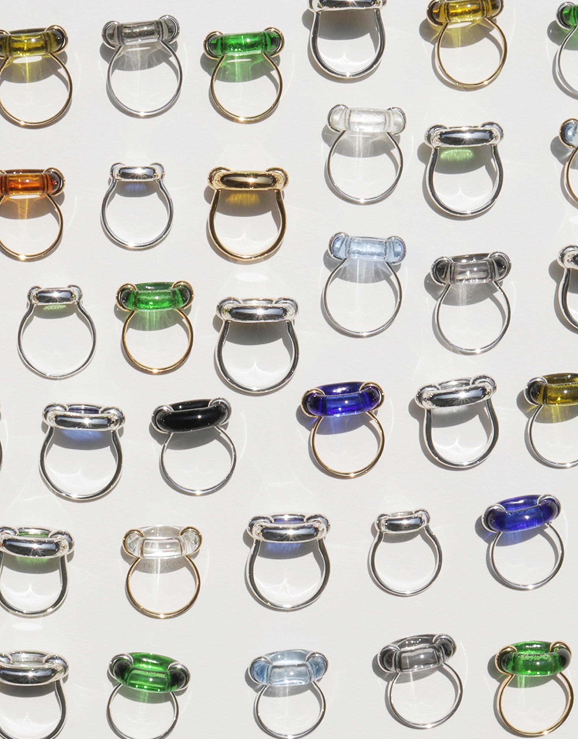 Array of Core Loop Rings in various colors and sizes, featuring eco gems seamlessly encased in metal settings. Rings display unique mirror-like surfaces, reflecting light and showcasing the intricate design. Stylish and functional jewelry pieces by CLED. Core Loop Ring | Large