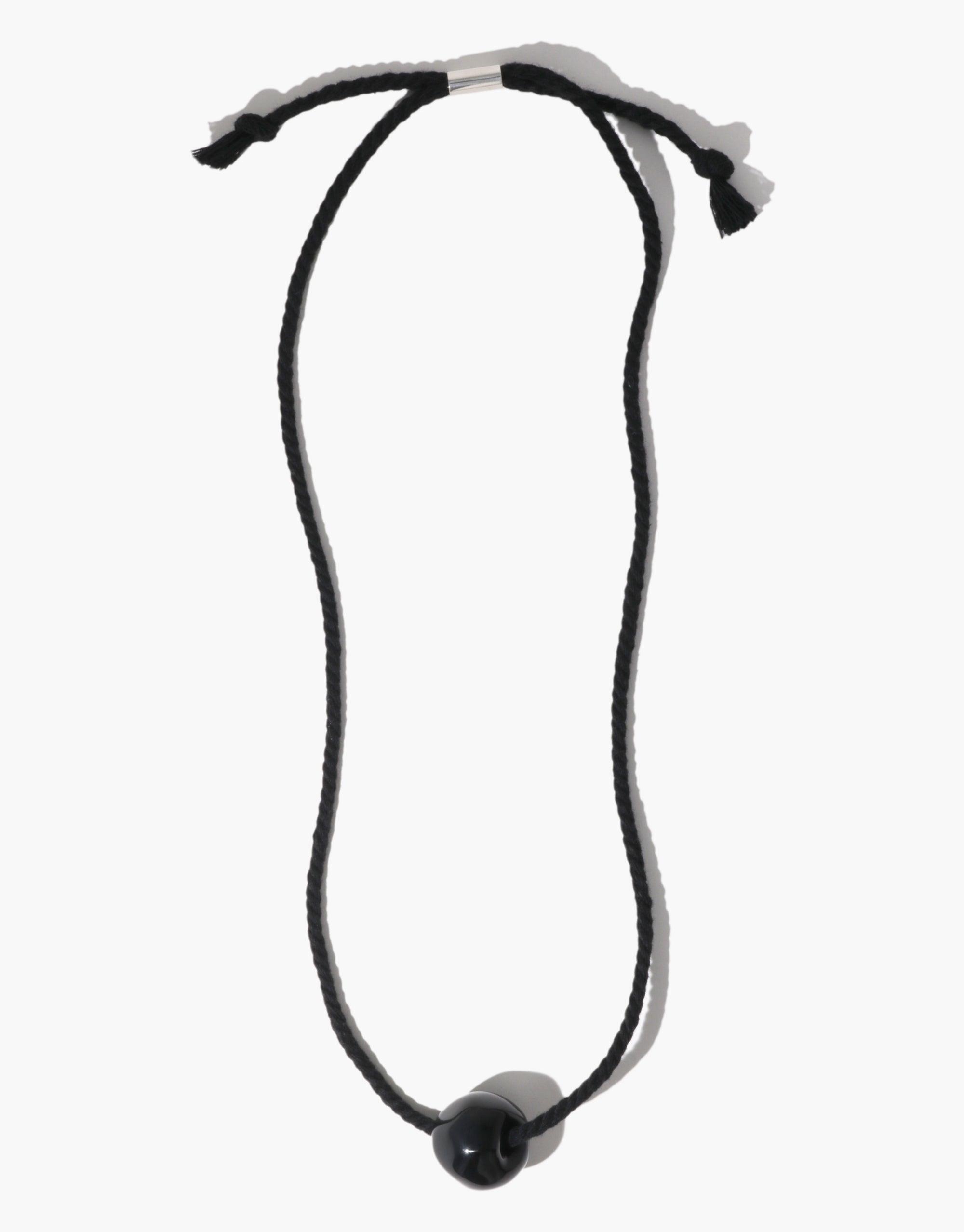 Elegant Black Pea Necklace featuring a single spherical pendant on a sleek cord, inspired by nature's organic shapes and transformation. Minimalist design showcases the beauty of simplicity and growth. Black Pea Necklace by CLED