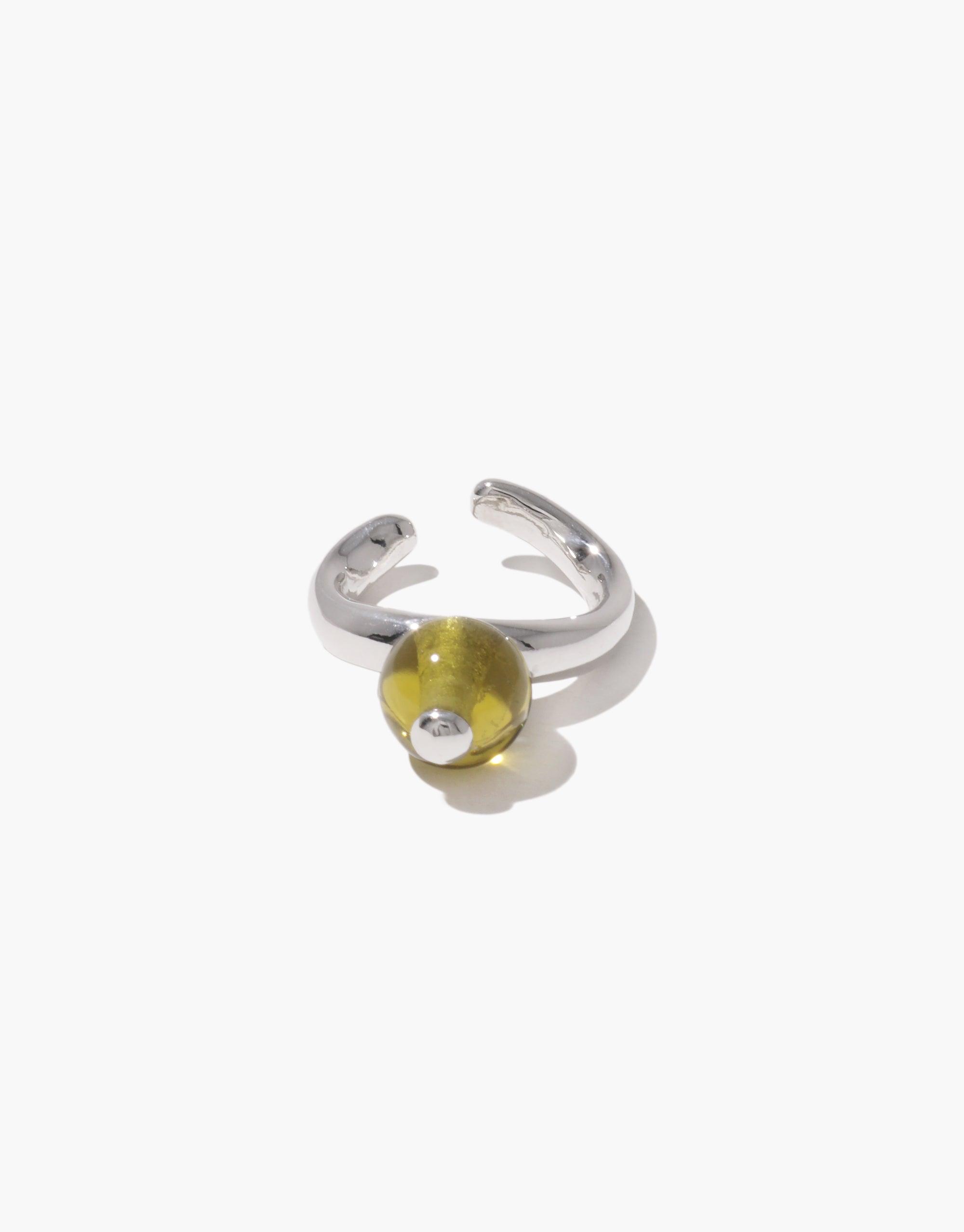 Pea Ear Cuff | Large featuring a silver-toned adjustable band with a vibrant yellow-green sphere, reminiscent of a pea pod. The design captures the organic shape and transformation of legumes, embodying nature's creativity. A unique piece inspired by the natural world. CLED