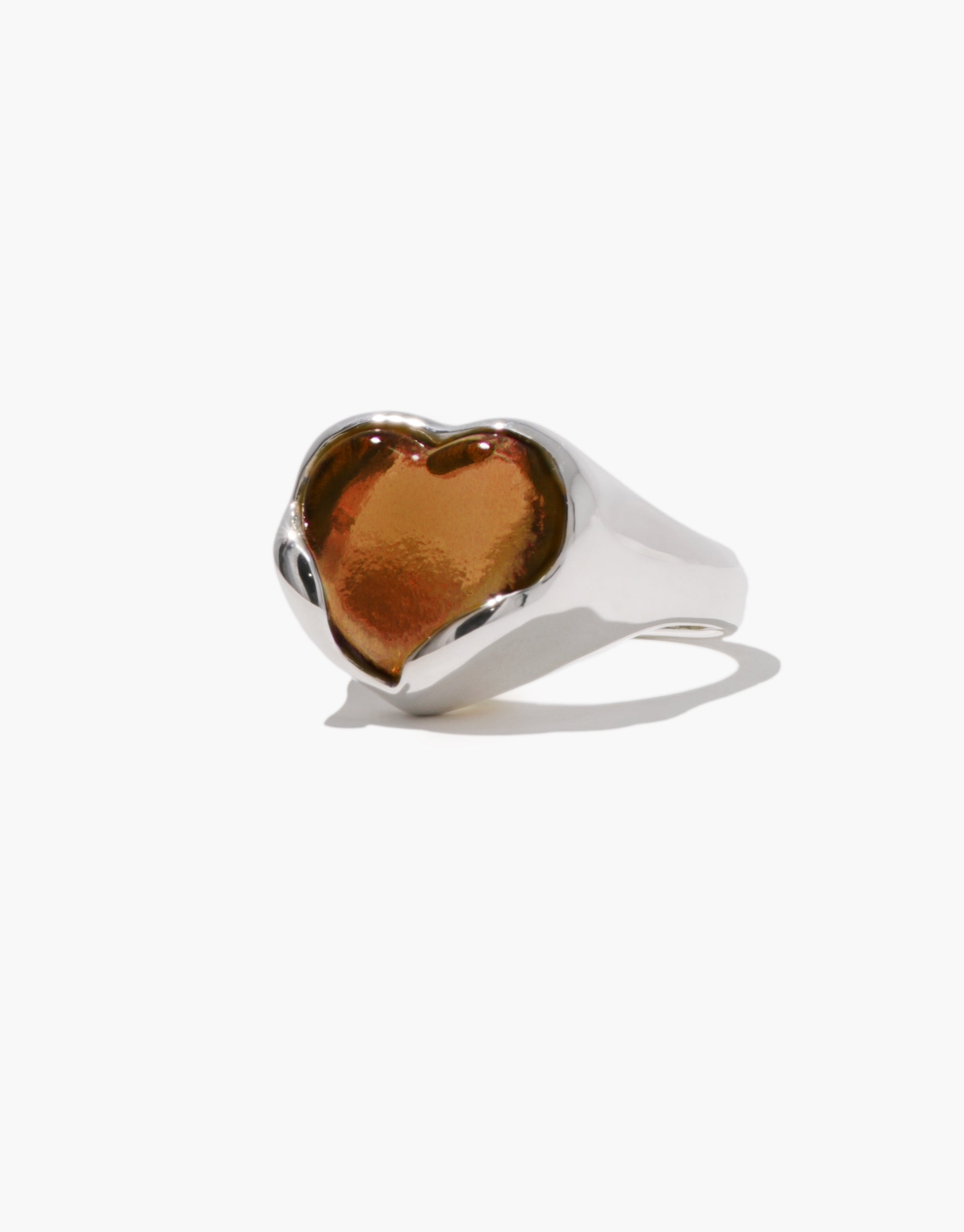 Side view of a silver ring with a warm amber-toned heart-shaped Eco Gem, set into a gently sculpted, reflective silver band.