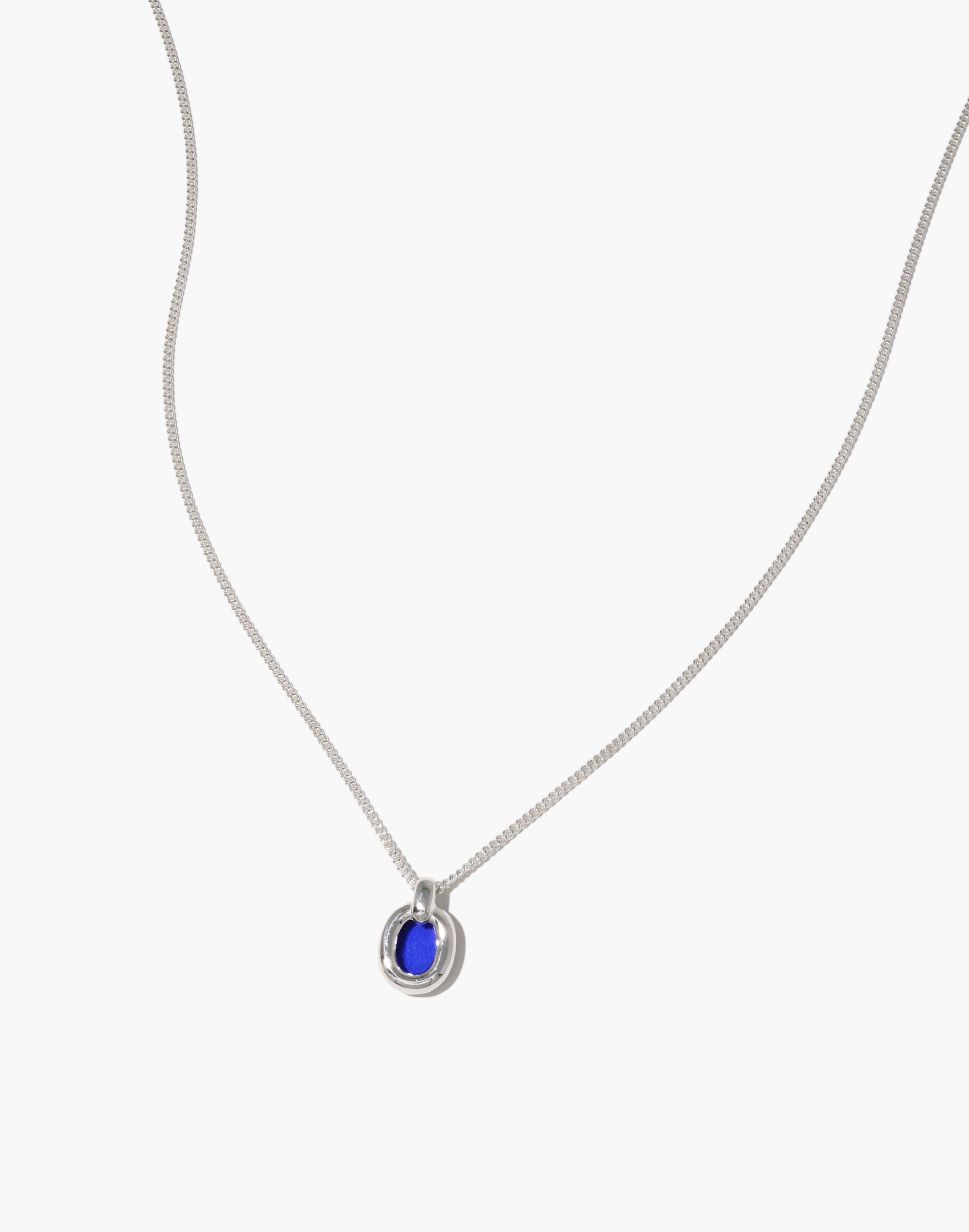 Elegant Small Core Loop Necklace featuring a delicate silver chain with a unique circular pendant. The pendant showcases a vibrant blue stone set within a silver loop, symbolizing unity and connection. A stylish, eco-friendly accessory from the In The Loop collection by CLED.