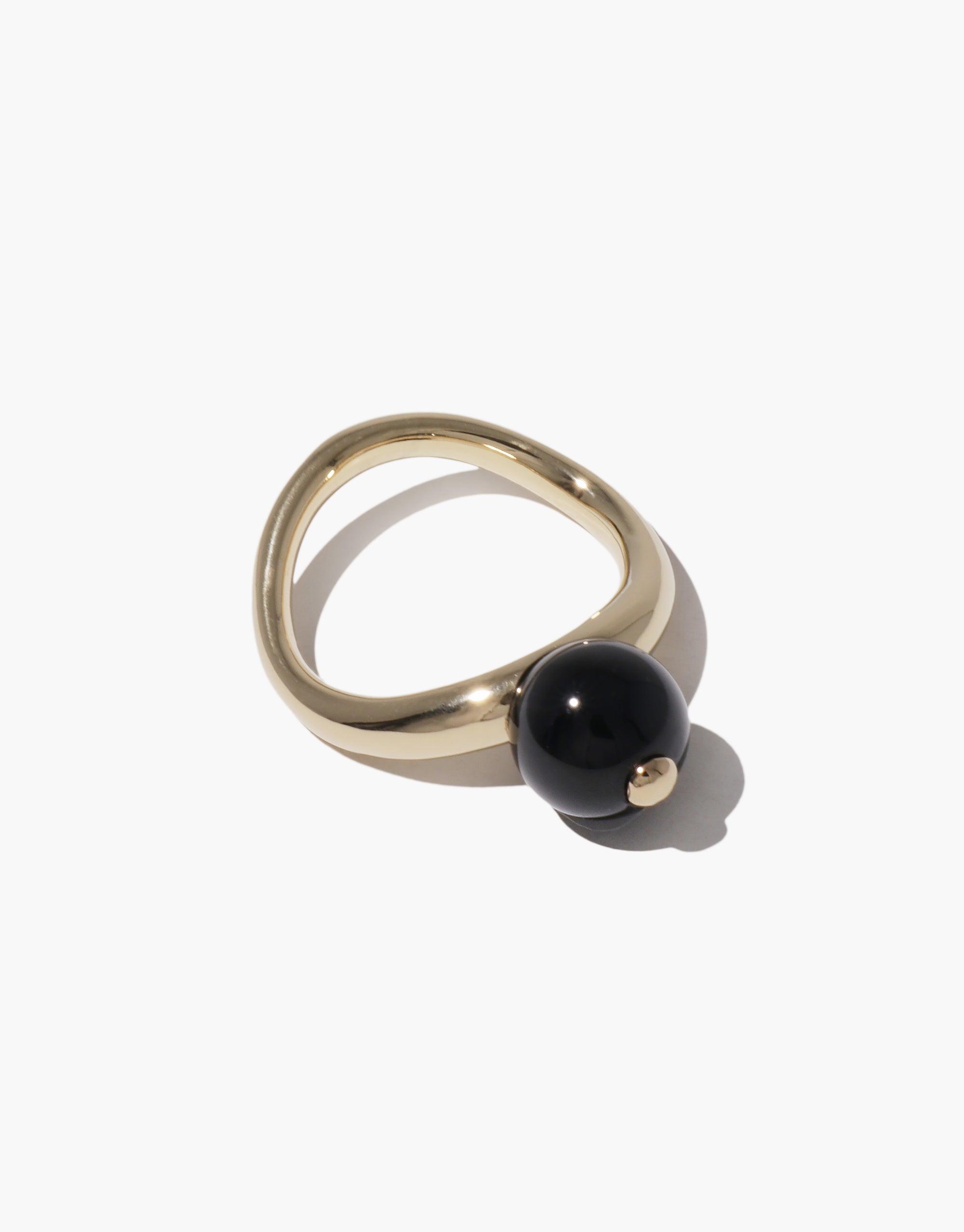 Elegant gold-toned ring with curved design featuring a single black spherical bead, inspired by organic legume shapes. Pea Curve Ring | Large showcases nature-inspired jewelry craftsmanship. CLED