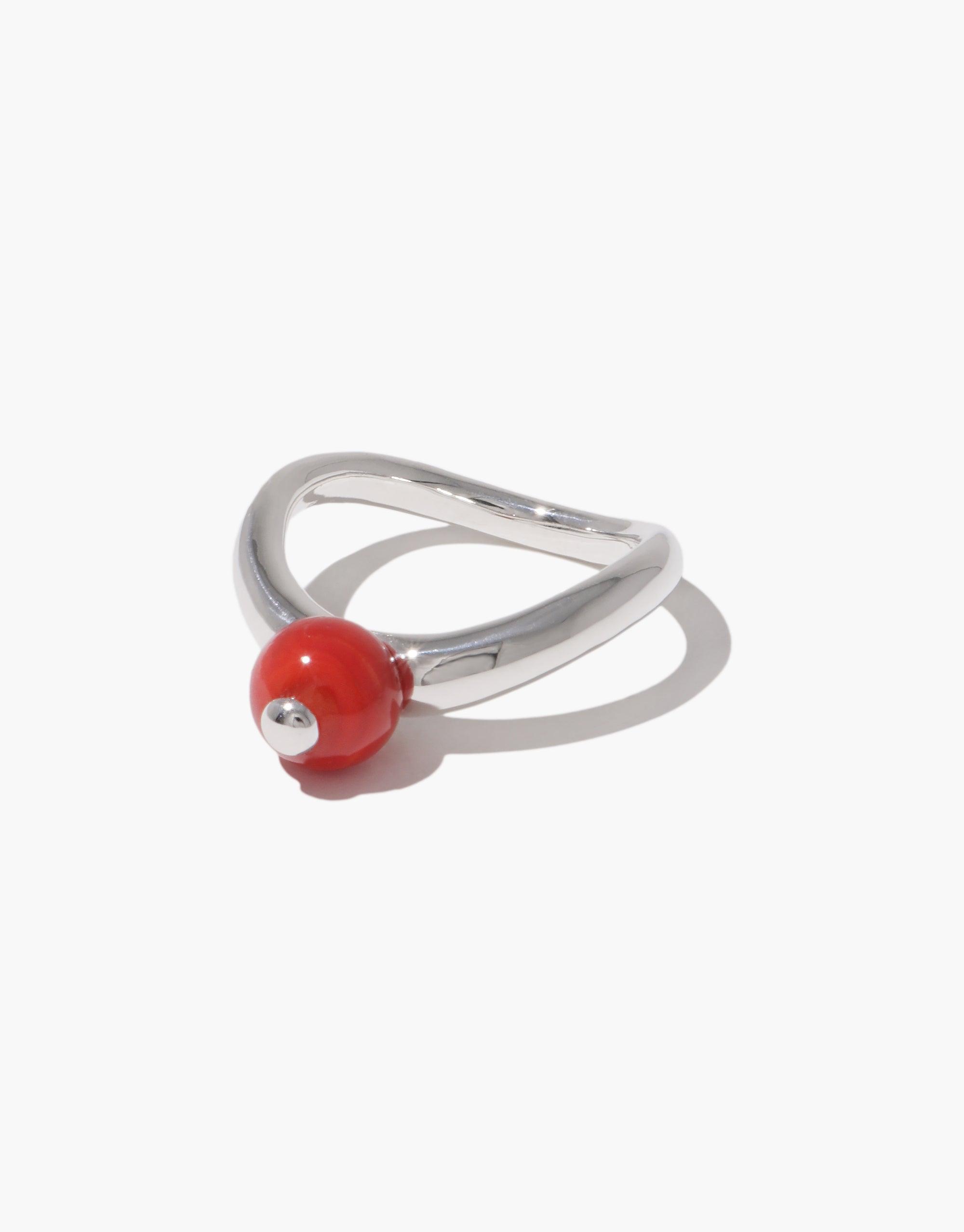 Sleek silver ring with curved design featuring a small red bead, inspired by organic legume shapes. Pea Curve Ring | Small showcases nature-inspired jewelry craftsmanship. Elegant and minimalist accessory for everyday wear. CLED