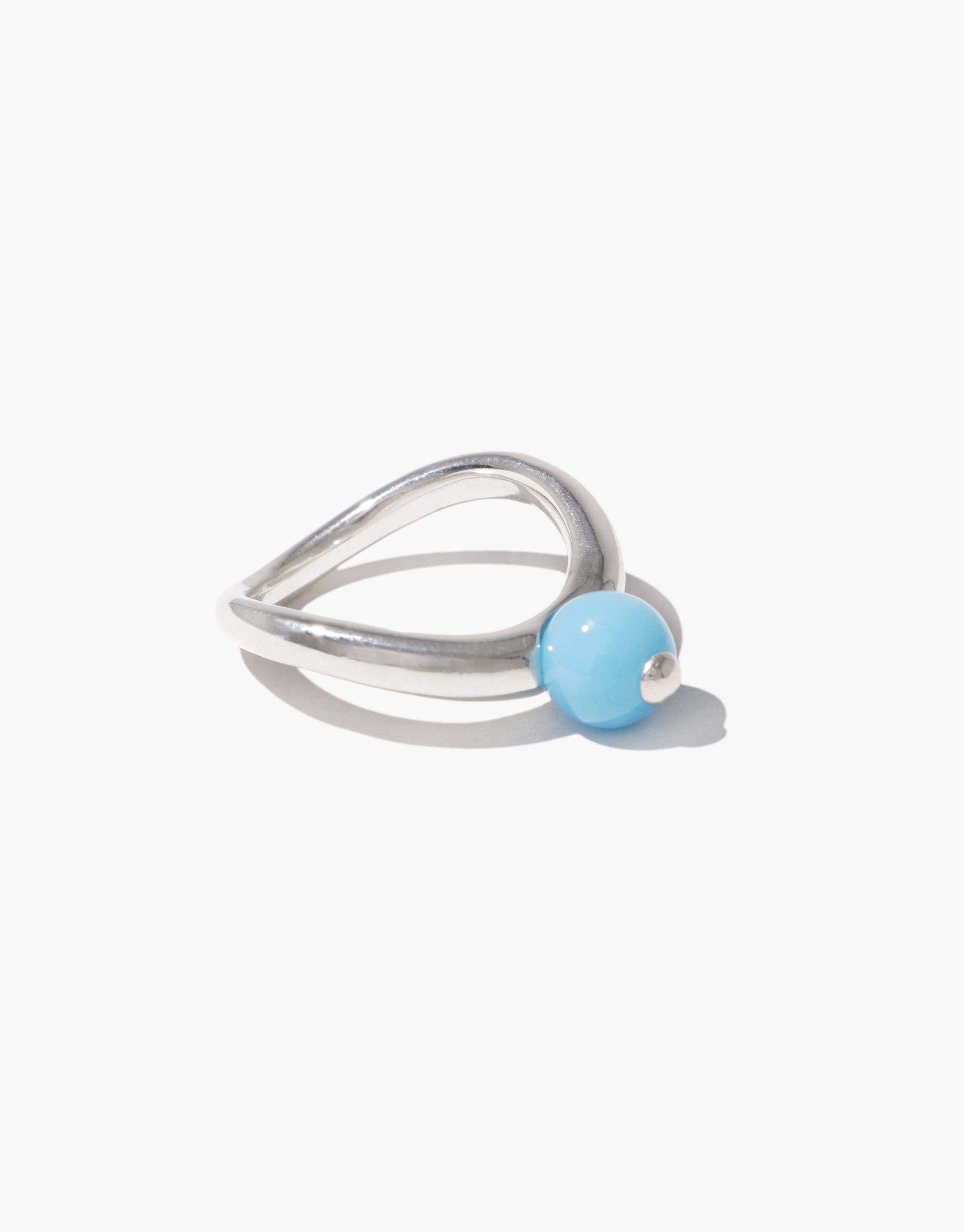 Pea Curve Ring | Small featuring a sleek silver band with graceful curves inspired by nature's legume shapes. A single light blue bead nestles within the organic design, symbolizing growth and transformation. Elegant and minimalist jewelry piece by CLED