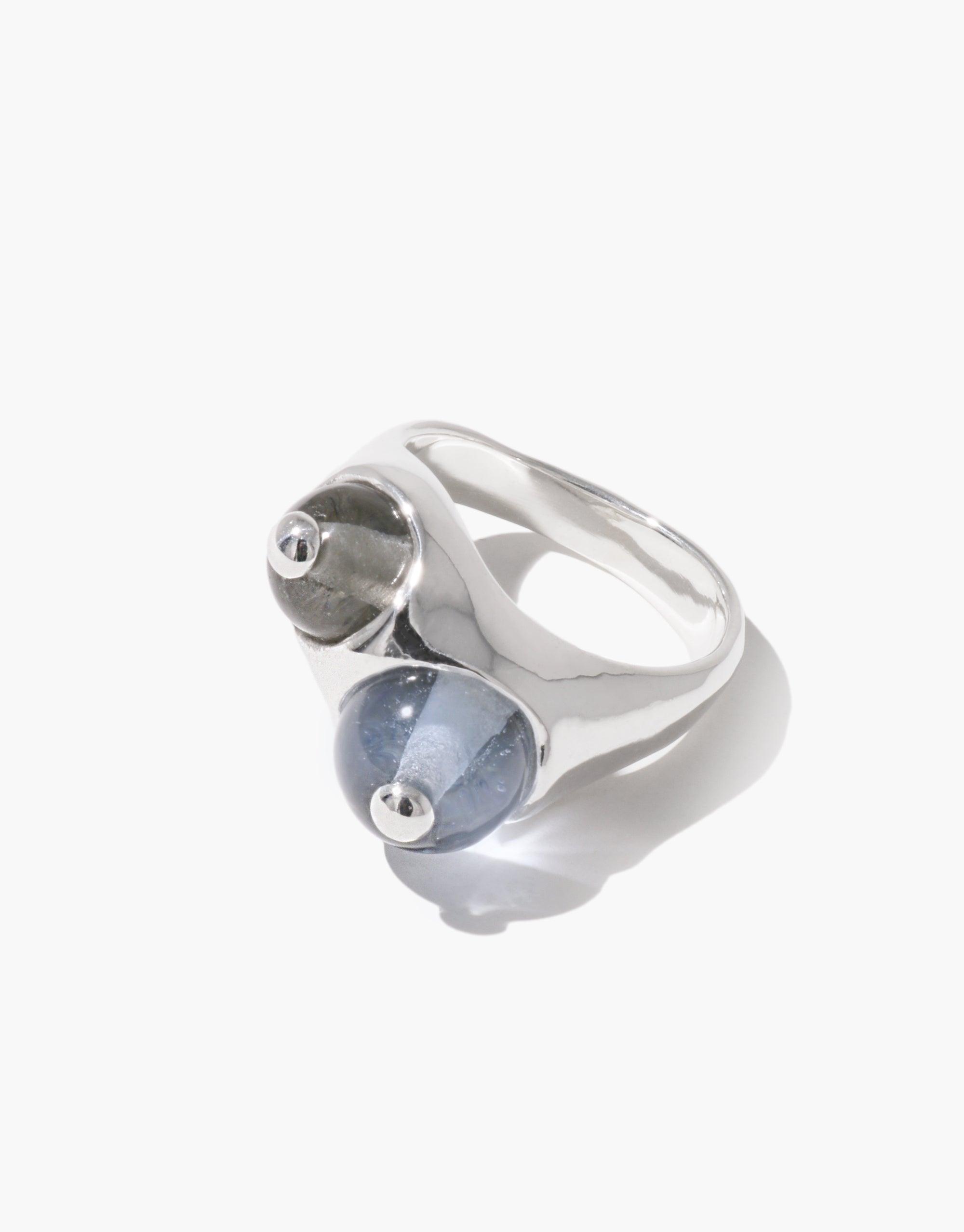 Elegant Pod Ring featuring two spherical elements in silver and blue-gray, inspired by organic legume shapes. Sleek metallic band showcases nature-inspired design. Unique jewelry piece reflecting growth and transformation. CLED Pod Ring.