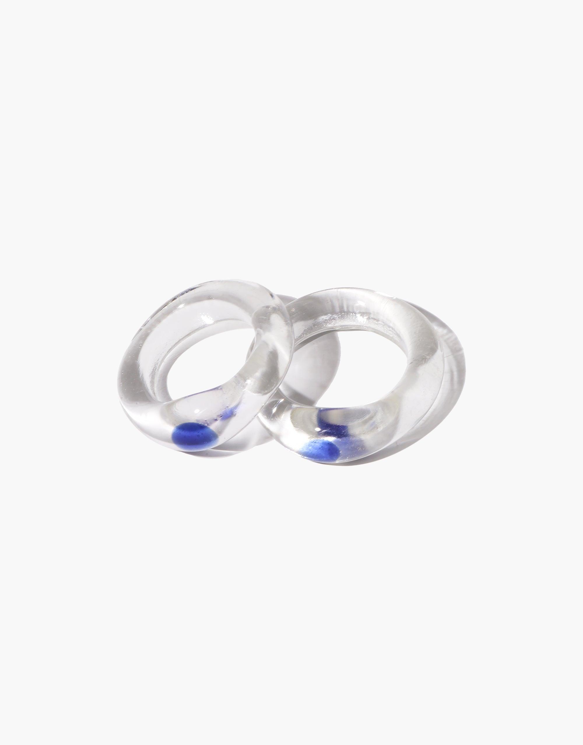 Two transparent glass rings with vibrant blue liquid inside, showcasing the unique design of the Blue Moon Ring. The rings appear smooth and polished, capturing light and creating a mesmerizing effect. A perfect blend of elegance and creativity in jewelry design. CLED Blue Moon Ring