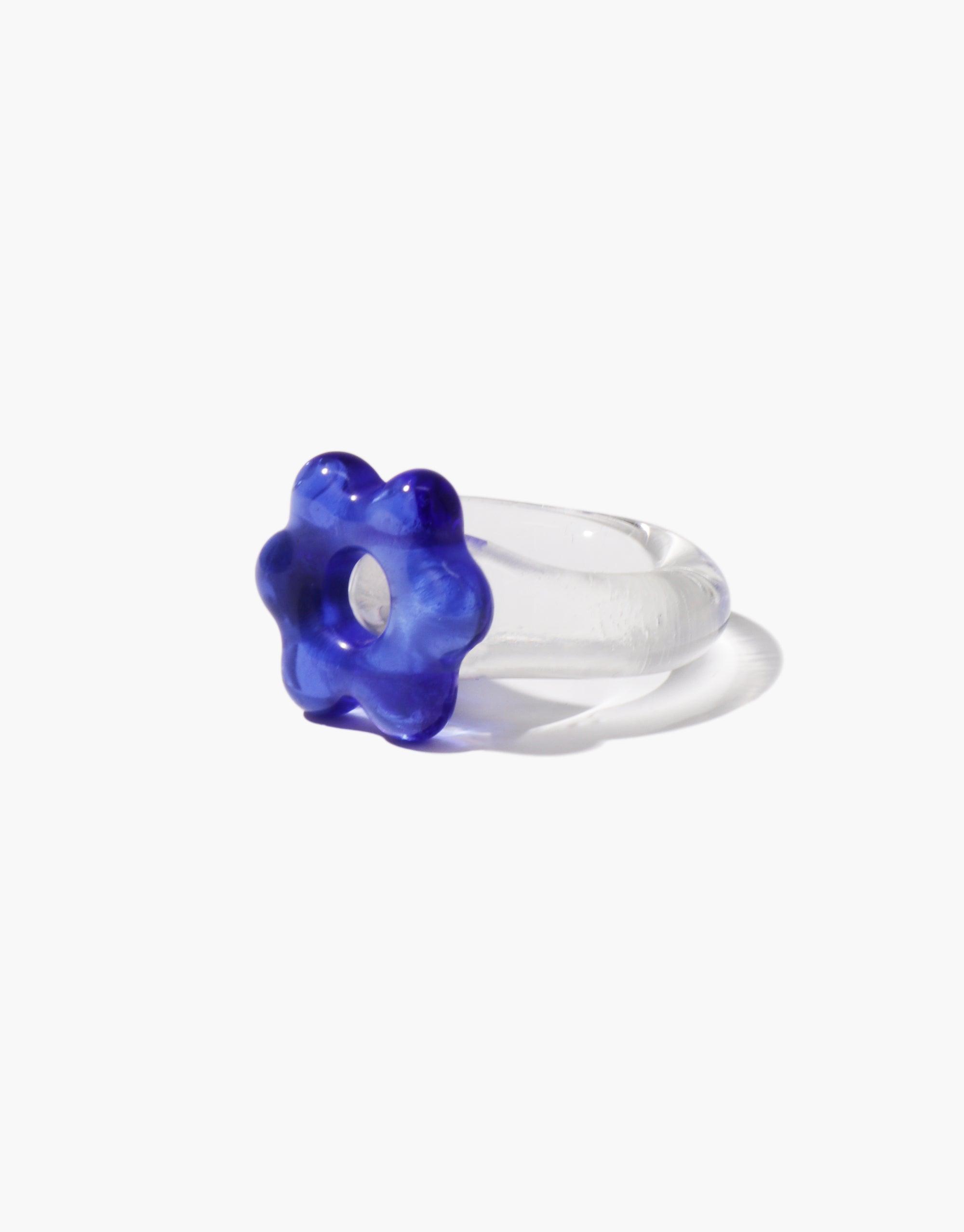 Whimsical large flower-shaped ring with vibrant blue glass blossom atop clear glass band. Avens Icon Ring | Large showcases unique design, blending transparency and color for a striking aesthetic. Handcrafted jewelry piece combining elegance and playfulness. CLED