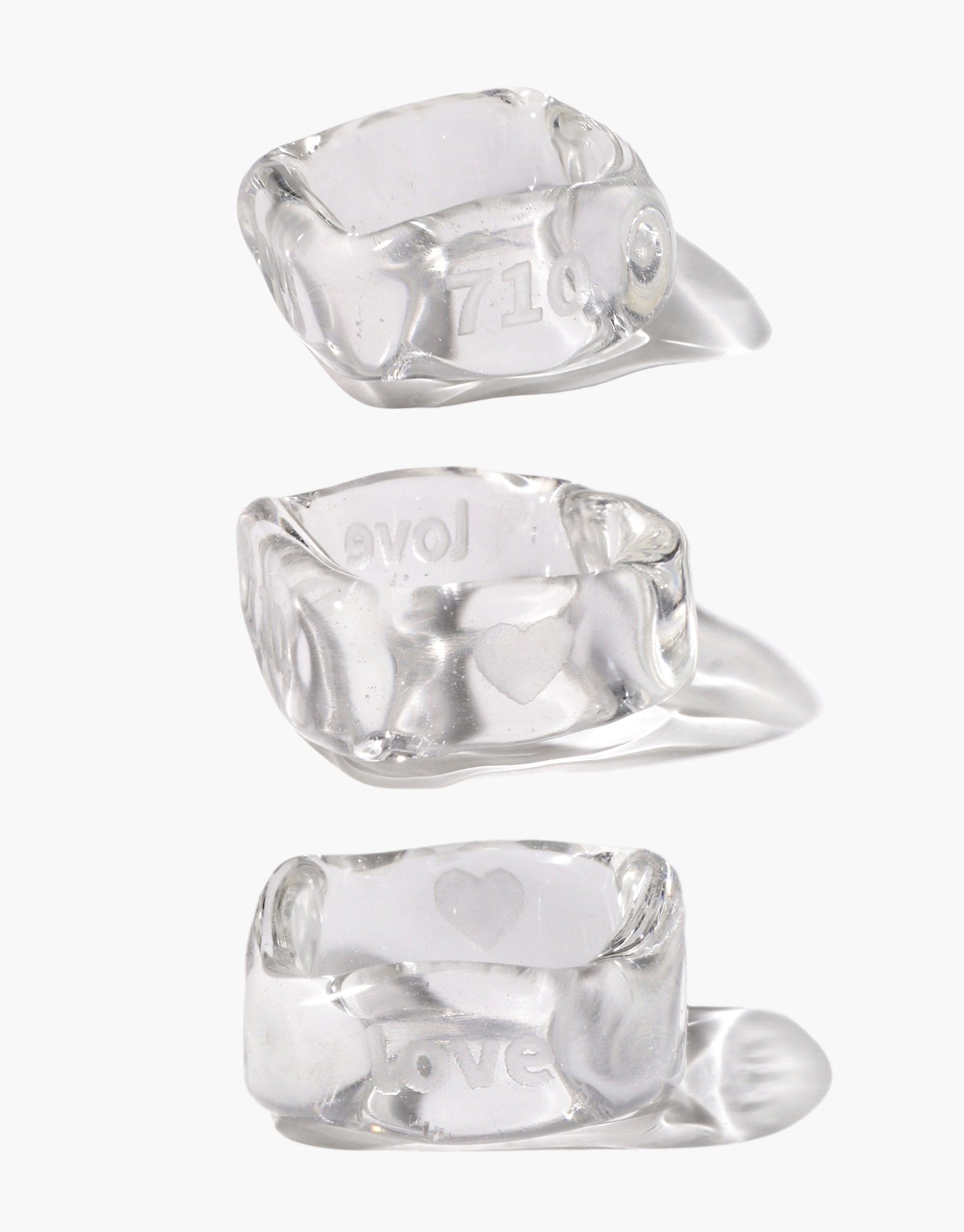 Three transparent Engravable Dice Rings with customizable sides for personalized engravings. Each ring features a unique, angular design resembling a clear crystal or ice cube, showcasing the potential for custom etching. Durable and stylish accessory for personalized jewelry enthusiasts. CLED Engravable Dice Ring.