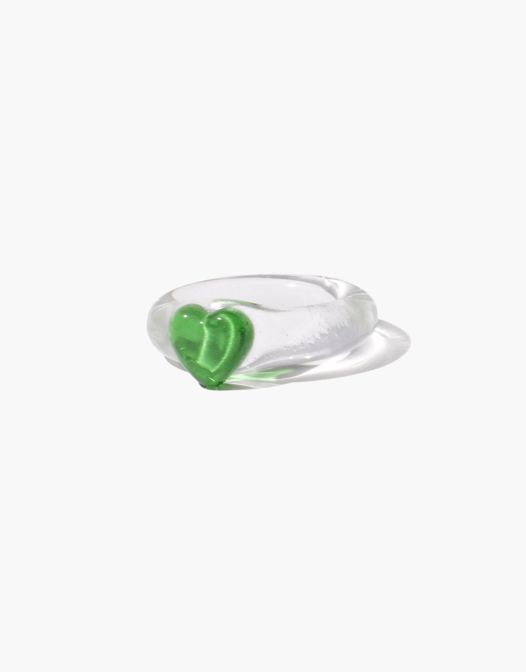 Clear glass ring with small green heart-shaped icon, minimalist design, transparent band, delicate and elegant appearance. Heart Icon Ring | Small, perfect for everyday wear or special occasions. CLED