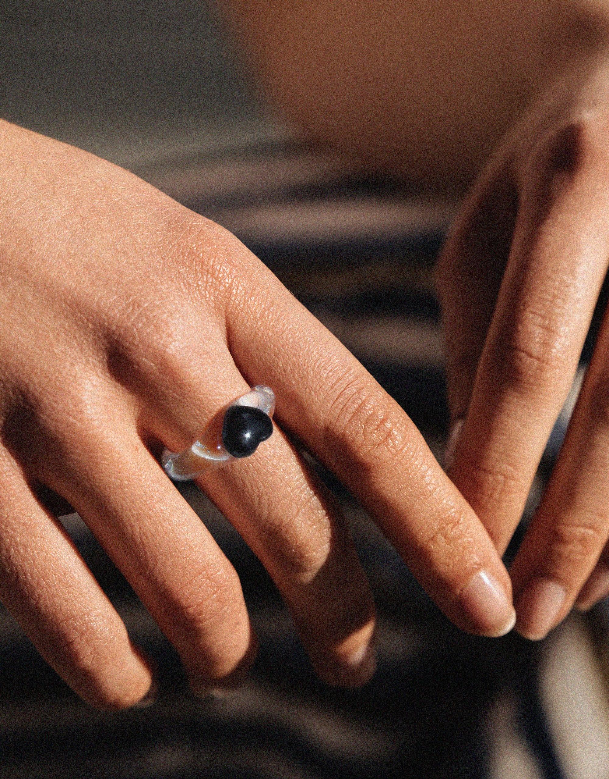 Close-up of a hand wearing a small silver ring with a dark, heart-shaped stone. The ring is showcased on the ring finger, highlighting its delicate design and elegant appearance. Heart Icon Ring | Small by CLED