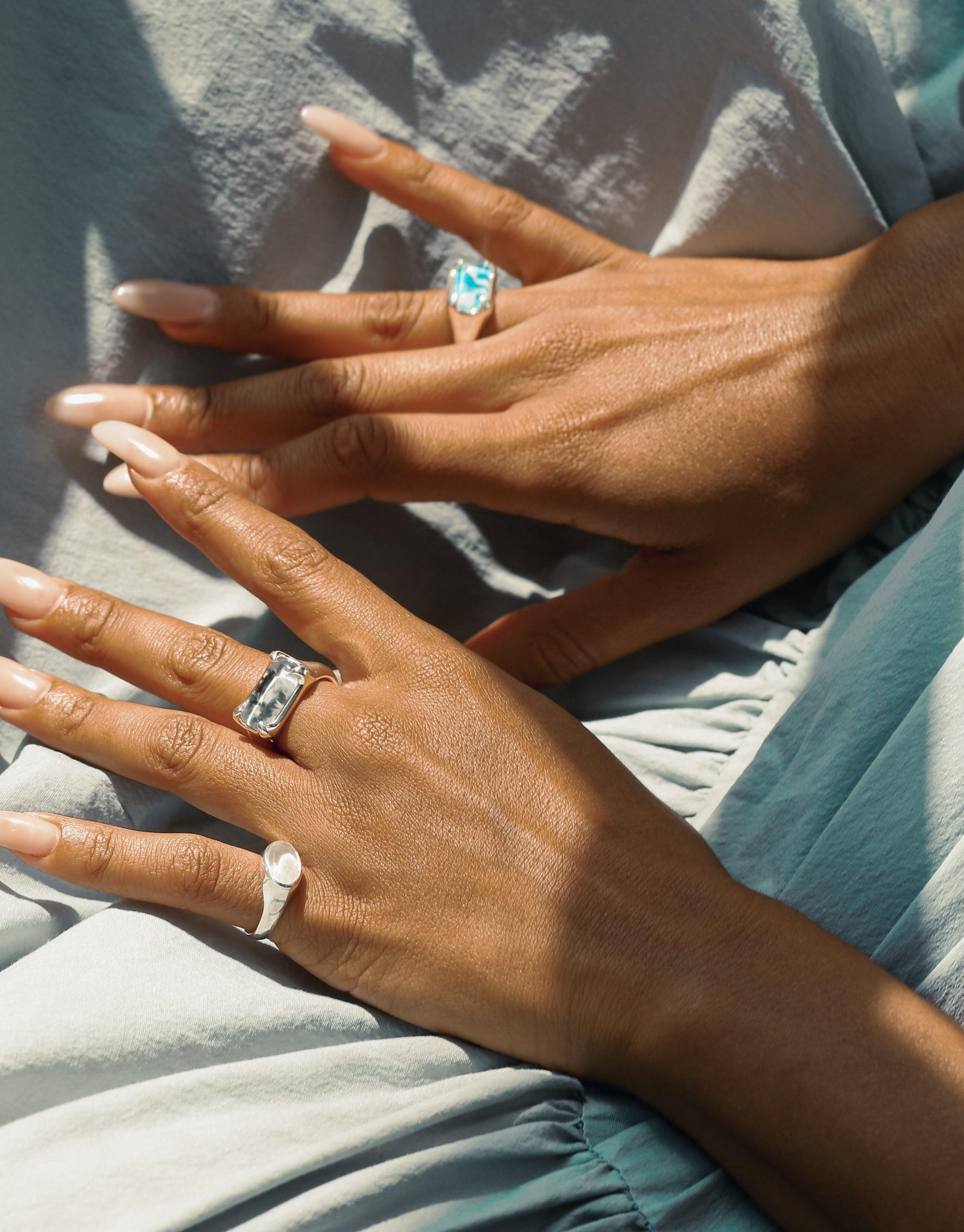Hands displaying Oval Sculpture Ring and other unique jewelry pieces, showcasing eco-friendly glass charms in various shapes and colors. Handcrafted rings with upcycled elements, reflecting sustainable luxury and artisanal design. Oval Sculpture Ring by CLED.