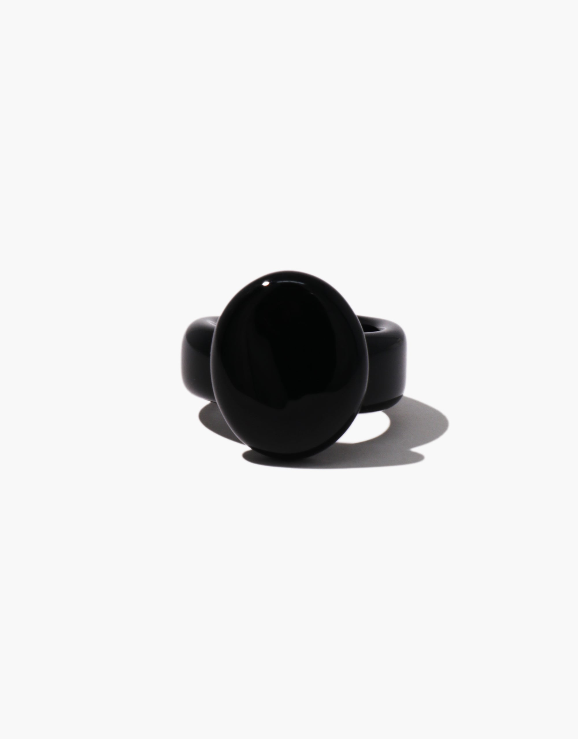 Side view of a glossy black statement ring with a domed oval top and a wide band, crafted from upcycled material.