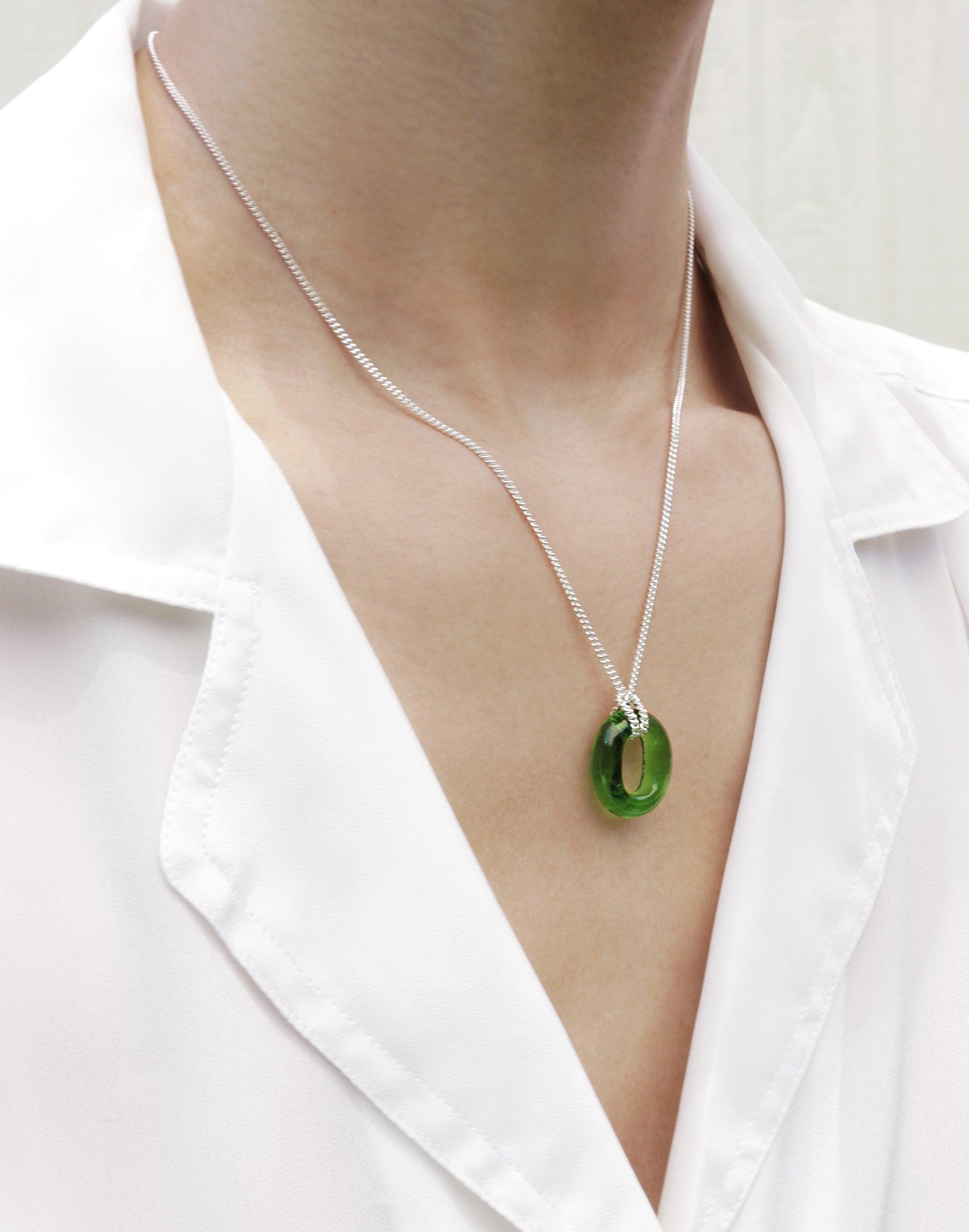 Elegant In The Loop Necklace featuring a green eco gem pendant on a silver chain, worn by a person in a white shirt. Showcases minimalist design and sustainable jewelry craftsmanship. CLED