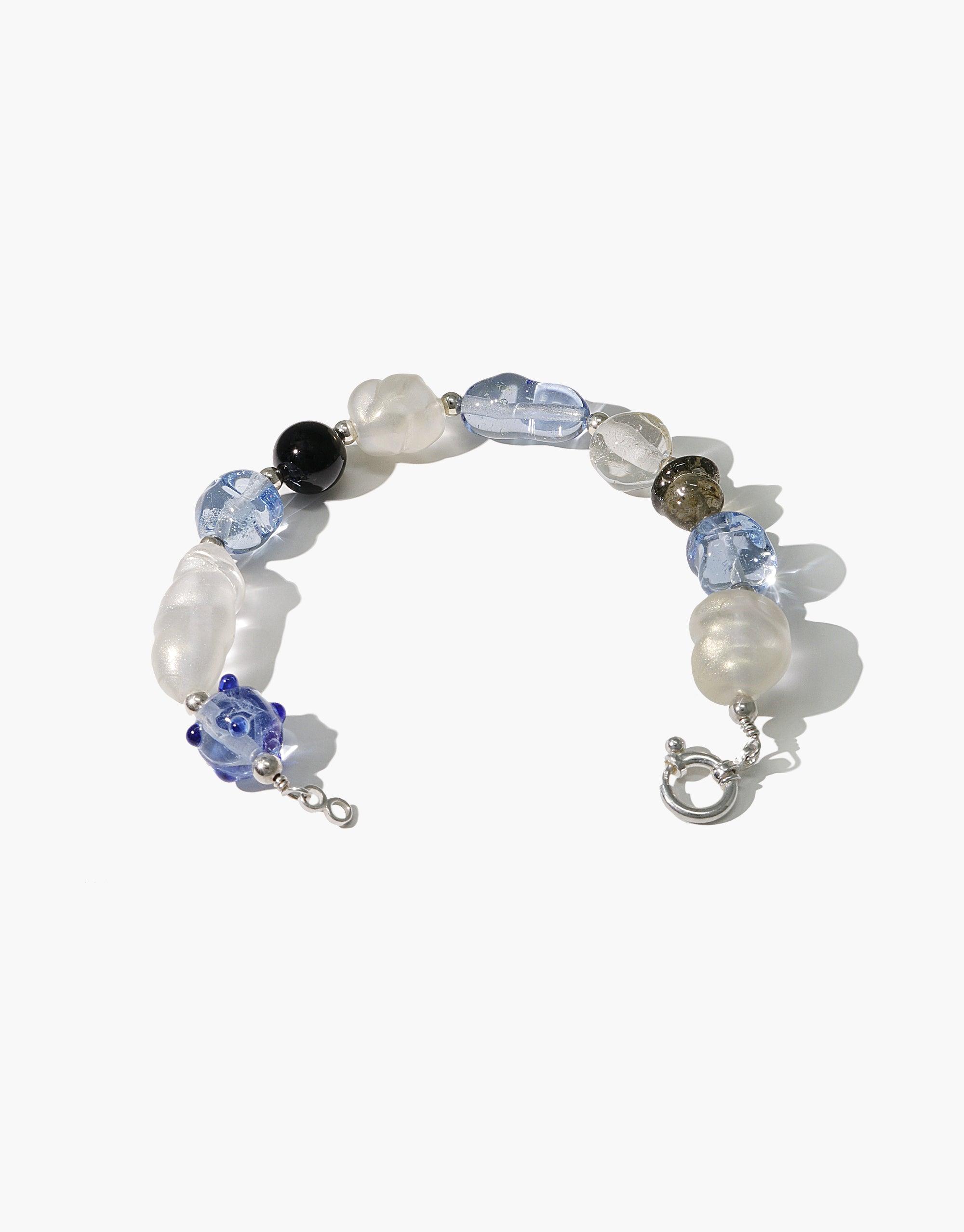 Blue Pearl Bracelet featuring a elegant mix of white, blue, and dark beads in various shapes and sizes, strung on a silver chain. Handcrafted eco-friendly jewelry piece with a sophisticated and versatile design. CLED
