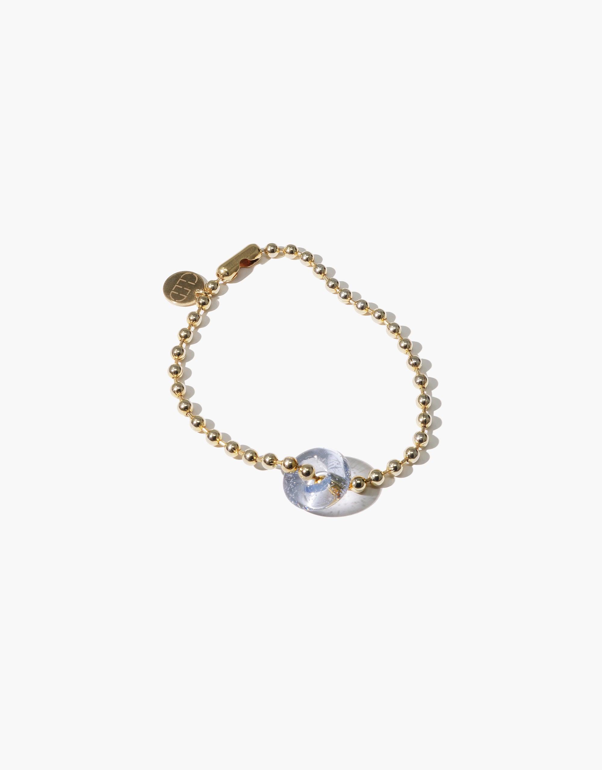 Elegant gold-toned beaded bracelet featuring a unique transparent eco gem centerpiece with prismatic reflections. Showcases sustainable luxury and handcrafted artistry in the Donut Ball Bracelet by CLED.
