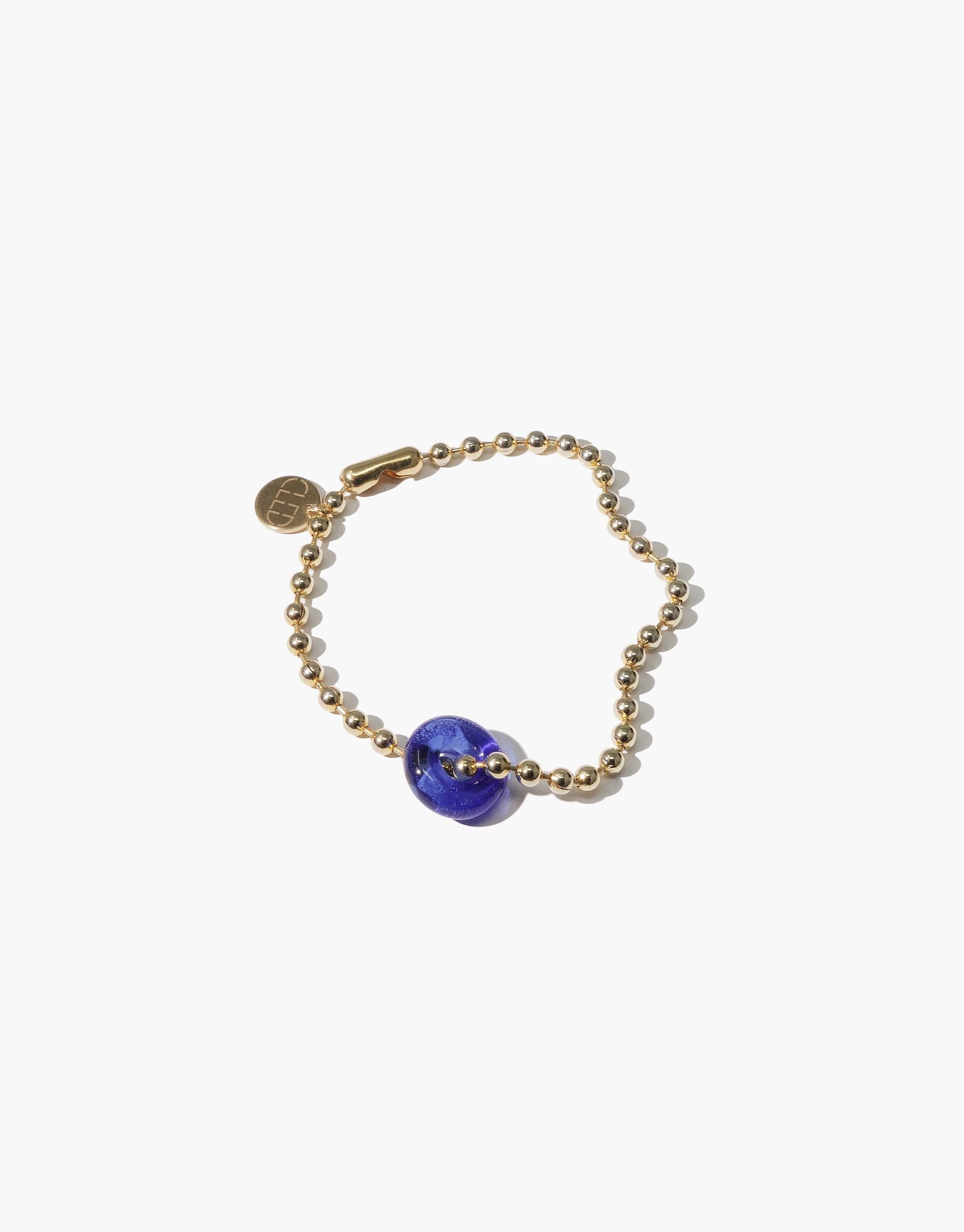 Donut Ball Bracelet featuring a vibrant blue eco gem bead on a gold-toned chain, with a small branded pendant. Handcrafted jewelry showcasing sustainable design and upcycled materials. Elegant and eco-friendly accessory by CLED.