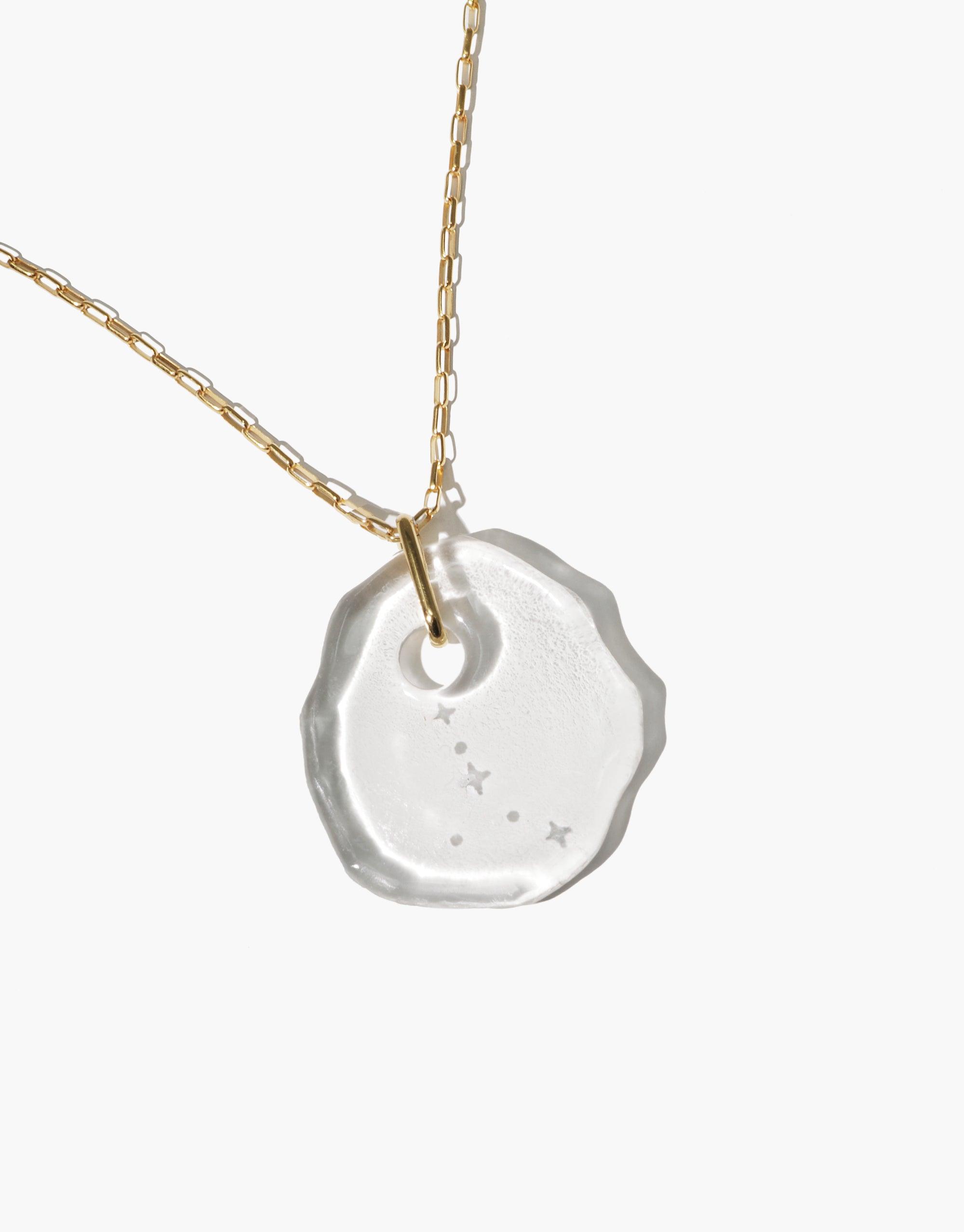 Handcrafted Constellation Necklace featuring an organic-shaped glass pendant with engraved zodiac stars on a delicate gold chain, showcasing eco-friendly elegance and celestial charm. Adjustable length for versatile styling. Constellation Necklace by CLED.