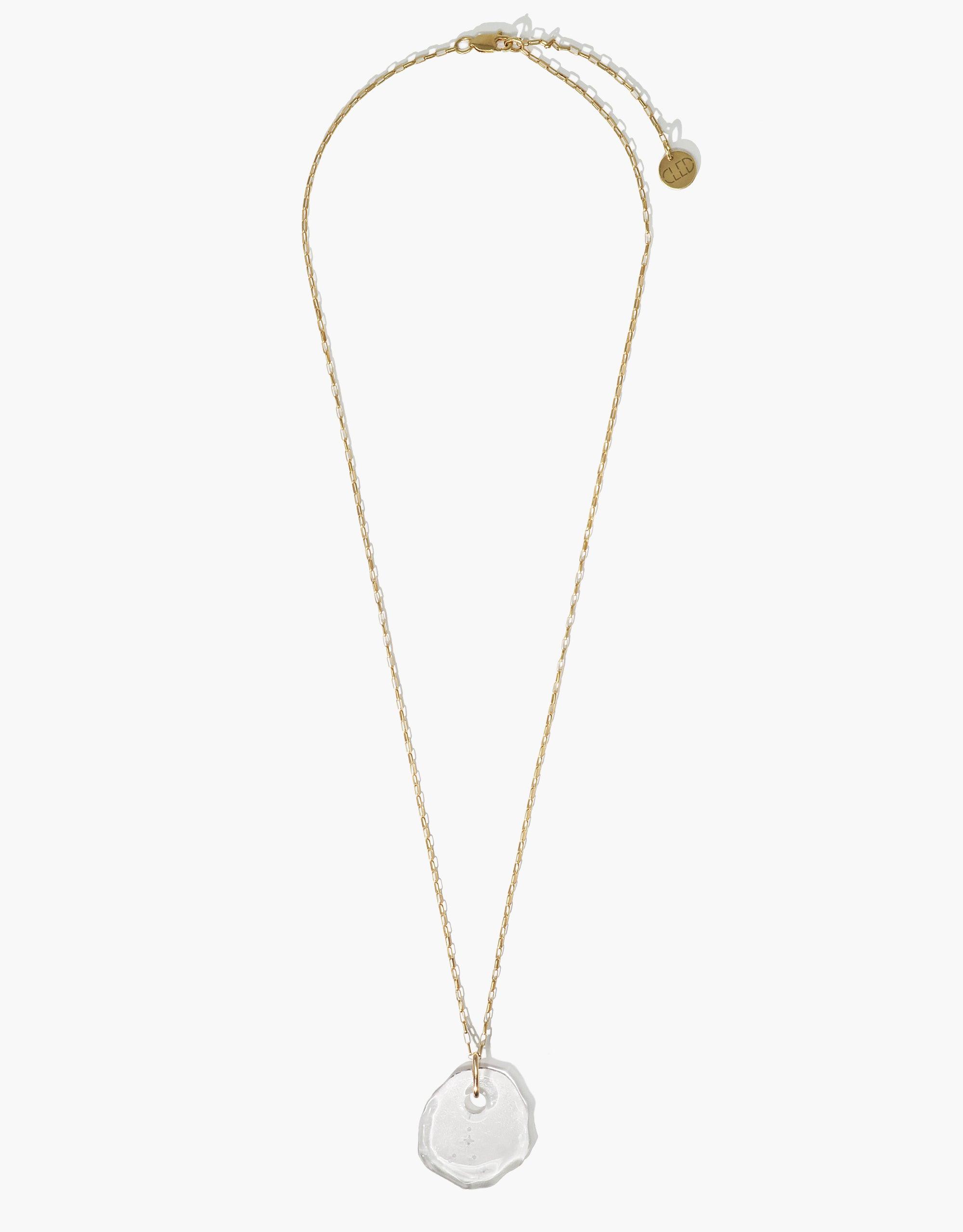 Elegant Constellation Necklace featuring a clear glass pendant with engraved zodiac star forms on a delicate gold chain. Adjustable length, eco-friendly design made from repurposed glass. Handcrafted piece from the Messenger Collection by CLED.