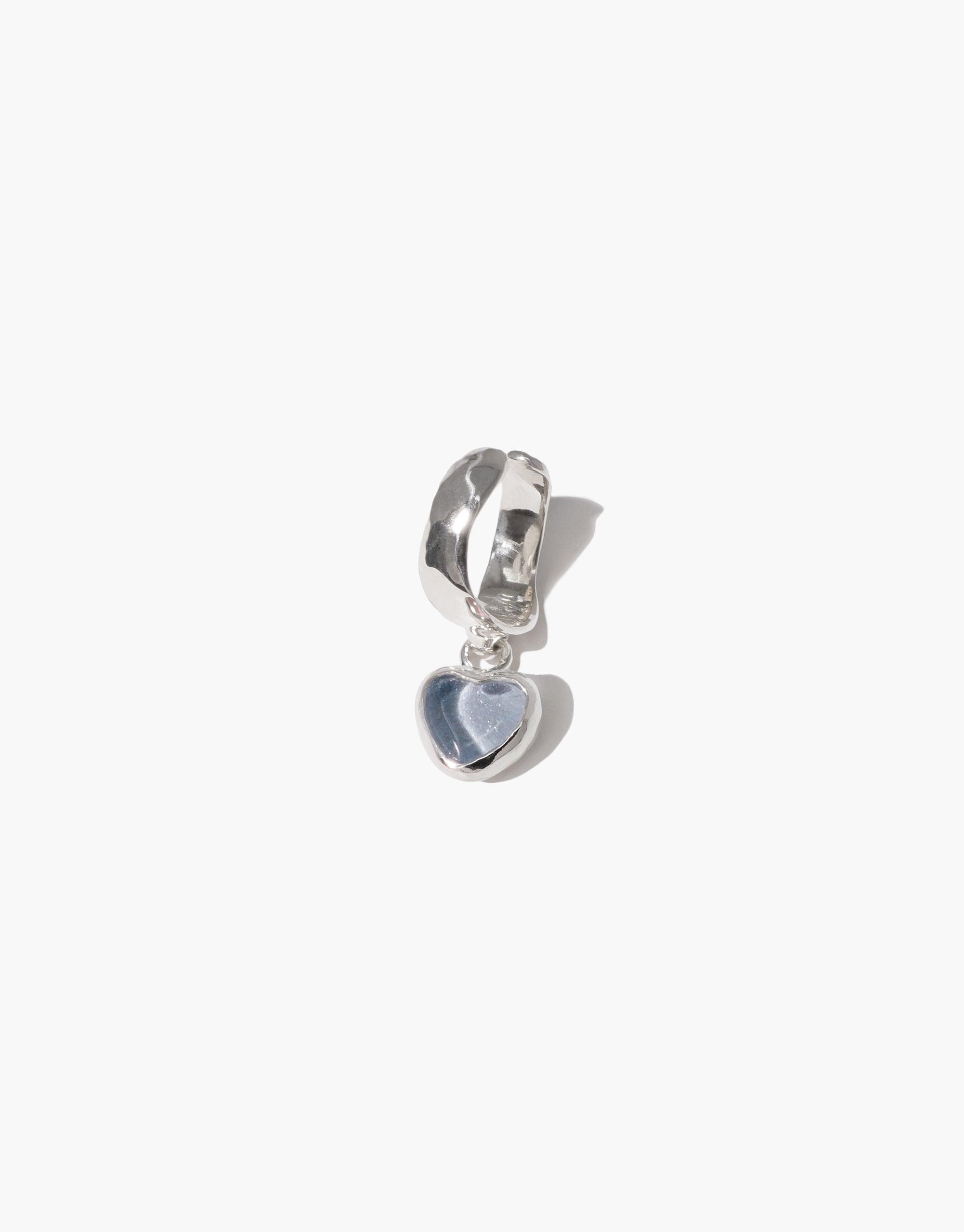 Silver ear cuff with a dangling heart-shaped charm made from upcycled glass. Elegant and eco-friendly jewelry piece showcasing a delicate design. Heart Dangling Ear Cuff by CLED.