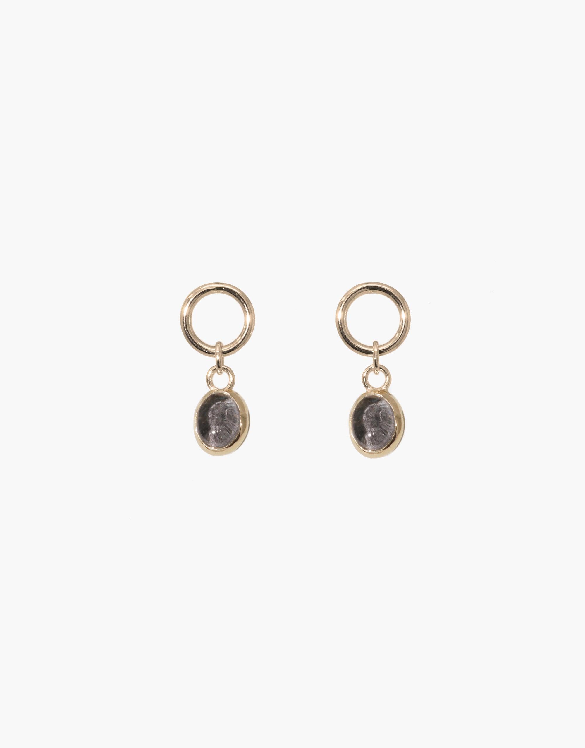 Elegant Oval Dangling Earrings featuring small gold hoops with oval-shaped grey glass charms. Handcrafted design showcases upcycled eco gems repurposed from discarded bottles. Sustainable and stylish jewelry perfect for everyday wear. Oval Dangling Earrings by CLED.