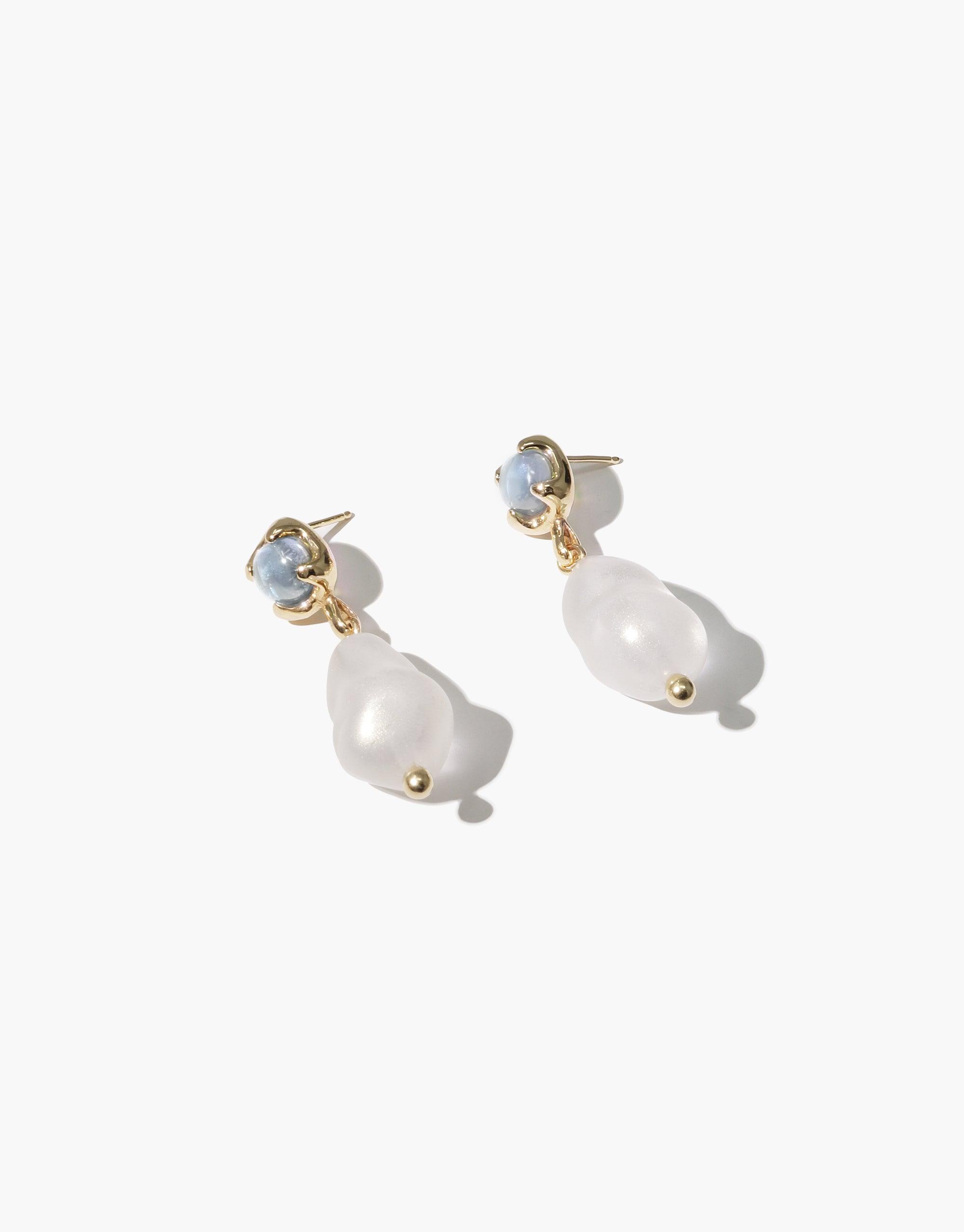 Elegant Beam Pearl Earrings featuring gold-toned studs with blue gemstones and dangling white pearl drops. Handcrafted design showcasing a blend of classic and modern aesthetics. Perfect for both casual and formal occasions. CLED