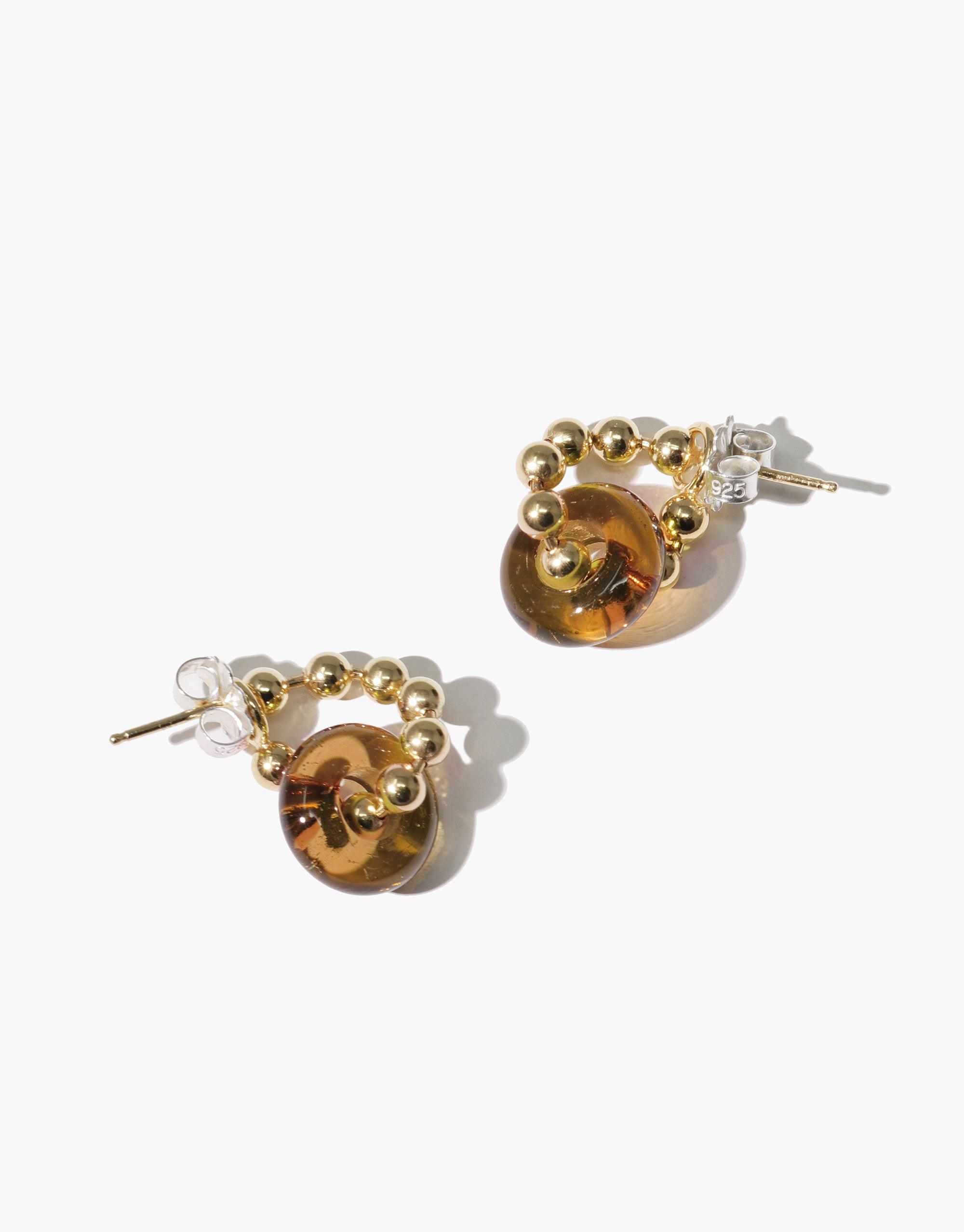 Donut Ball Hoop Earrings featuring golden spheres and amber-colored eco gems crafted from upcycled glass. Elegant and sustainable jewelry design with a playful twist. Handmade, eco-friendly accessories by CLED.