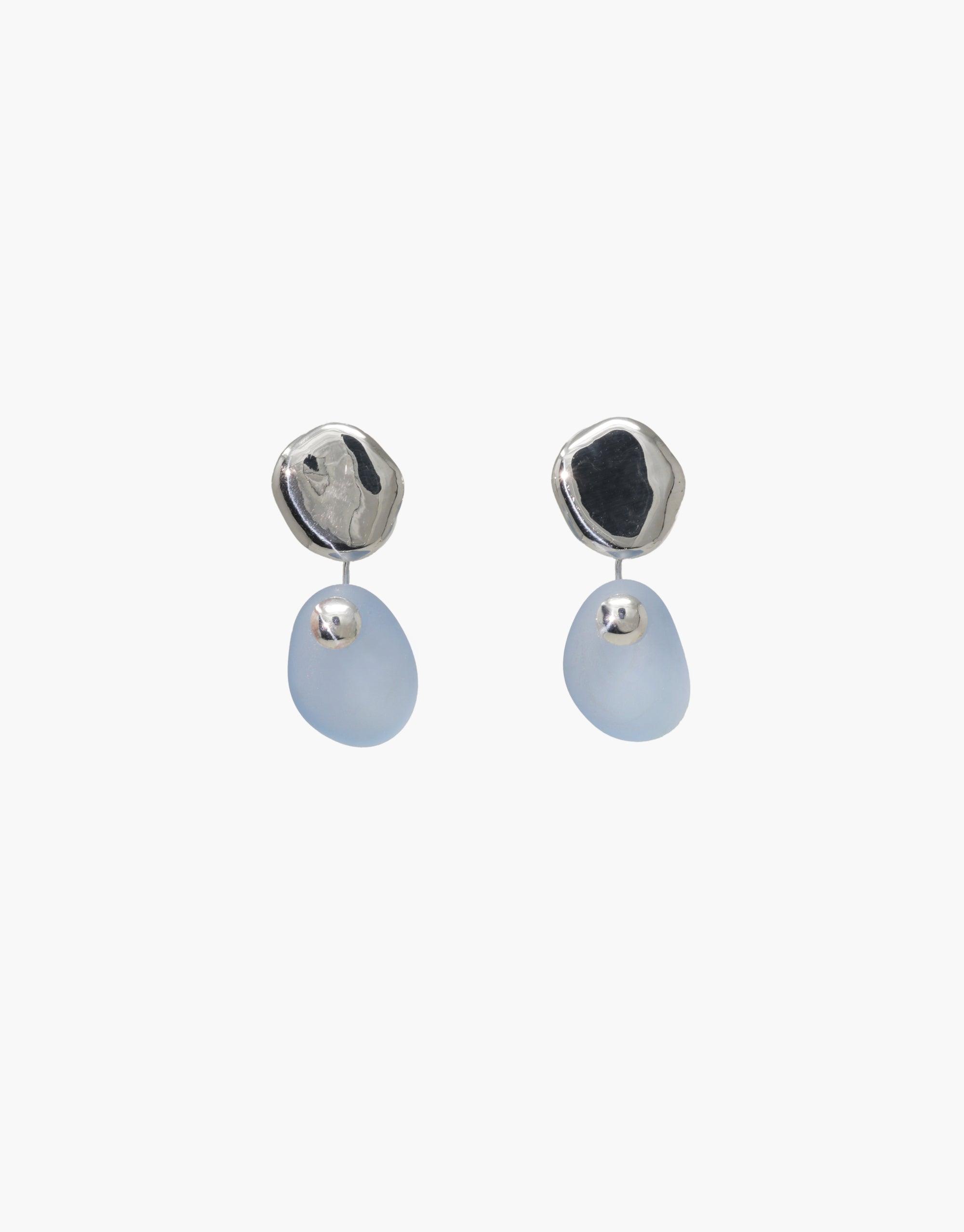 Elegant Pebble Earrings featuring silver-toned studs and translucent blue drop pendants. Handcrafted eco-friendly jewelry with organic shapes and subtle luminosity. Perfect for everyday wear or special occasions. Sustainable fashion accessory by CLED. Pebble Earrings.