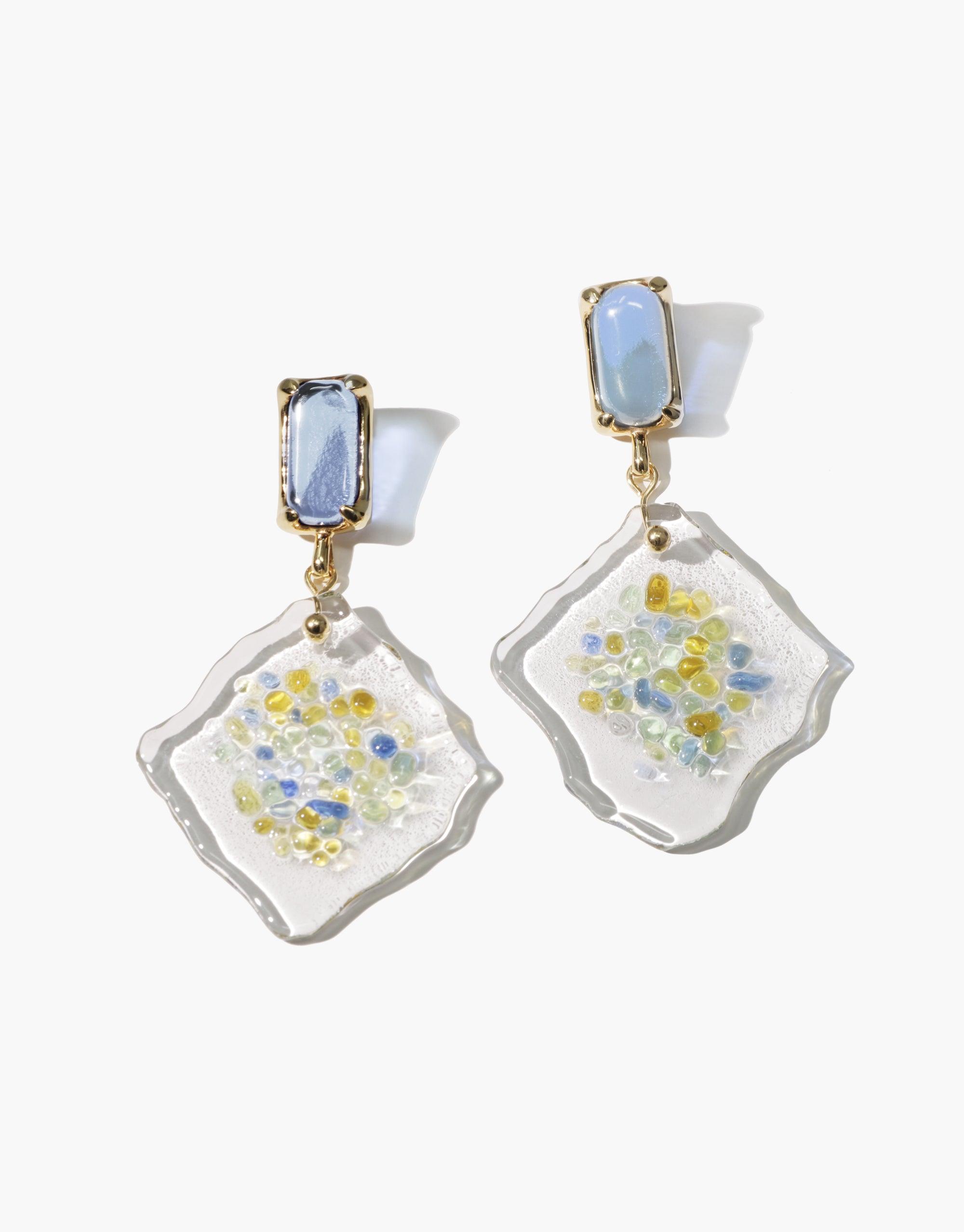 Spectral Prism Earrings featuring light blue eco gem studs and white diamond-shaped pendants with colorful glass fragments, showcasing sustainable jewelry design inspired by prismatic light refraction. Handmade, upcycled glass earrings by CLED.