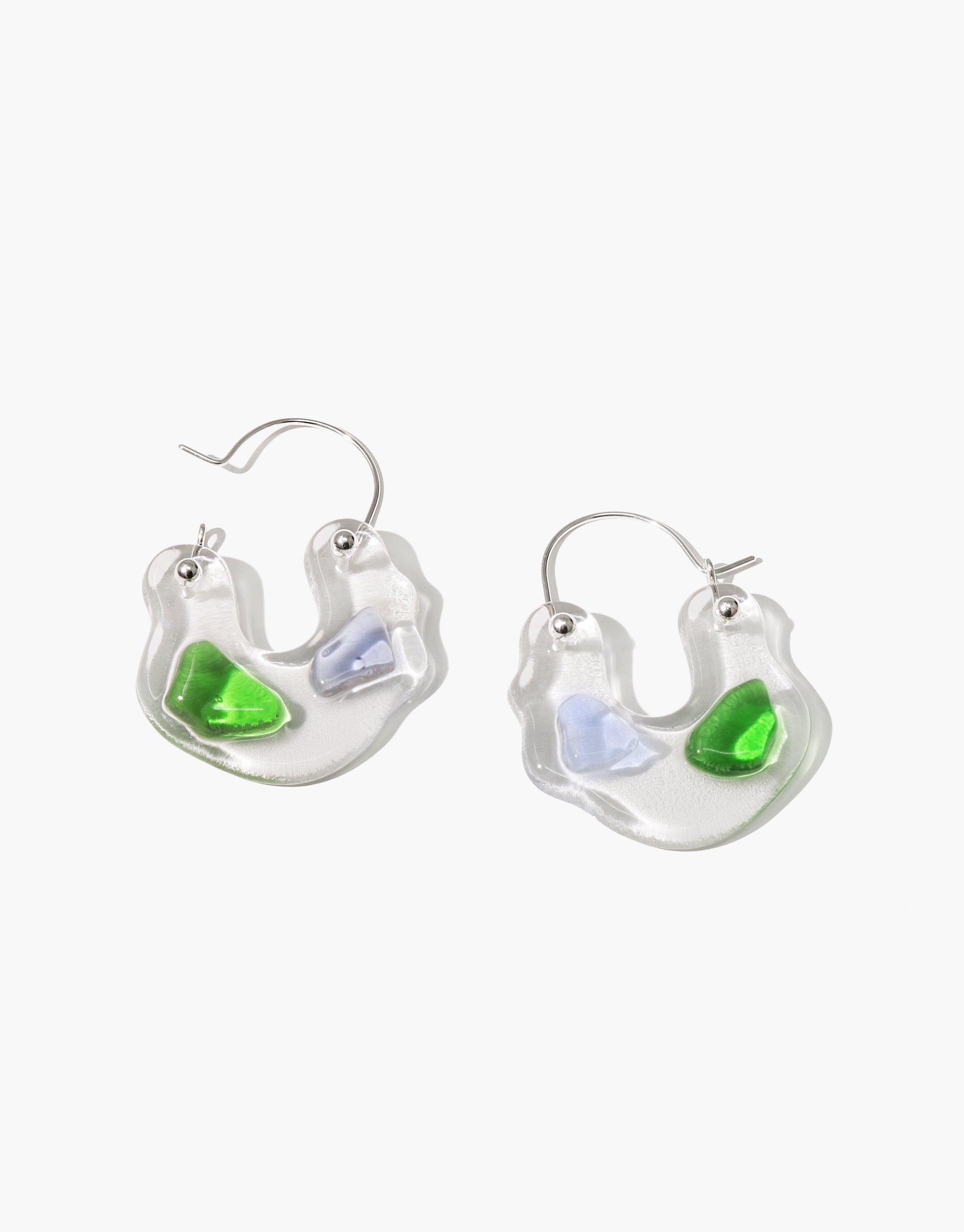 Ray Hoop Earrings featuring crescent-shaped clear glass with green and purple eco gem accents, handcrafted from upcycled bottles. Sterling silver hooks. Sustainable jewelry showcasing prismatic colors inspired by natural light refraction. CLED