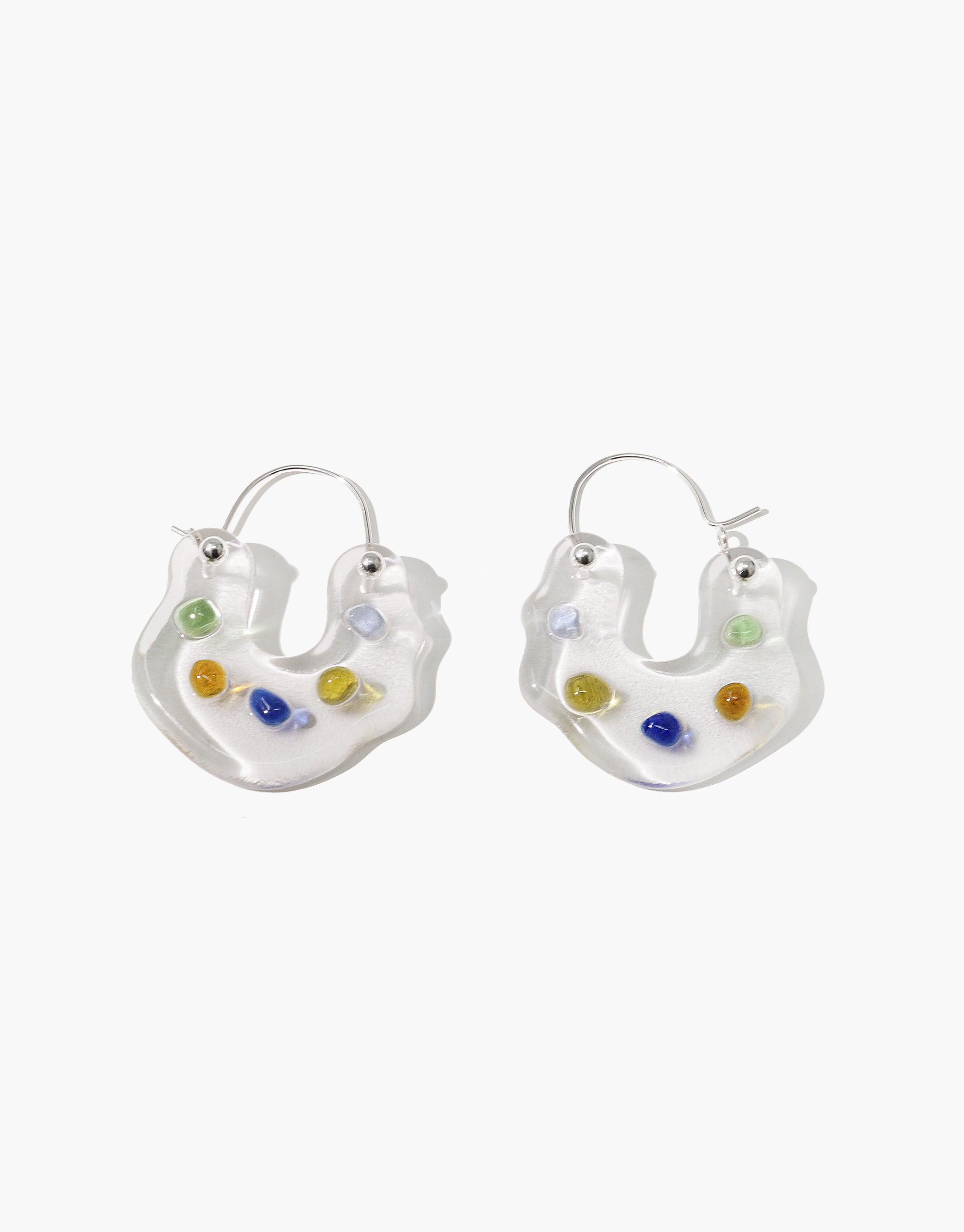 Ray Hoop Earrings featuring unique curved shapes with colorful eco gems embedded in translucent material. Sterling silver hooks for elegant, sustainable jewelry. Handmade design showcases prismatic colors inspired by natural light refraction. Eco-friendly accessory by CLED.