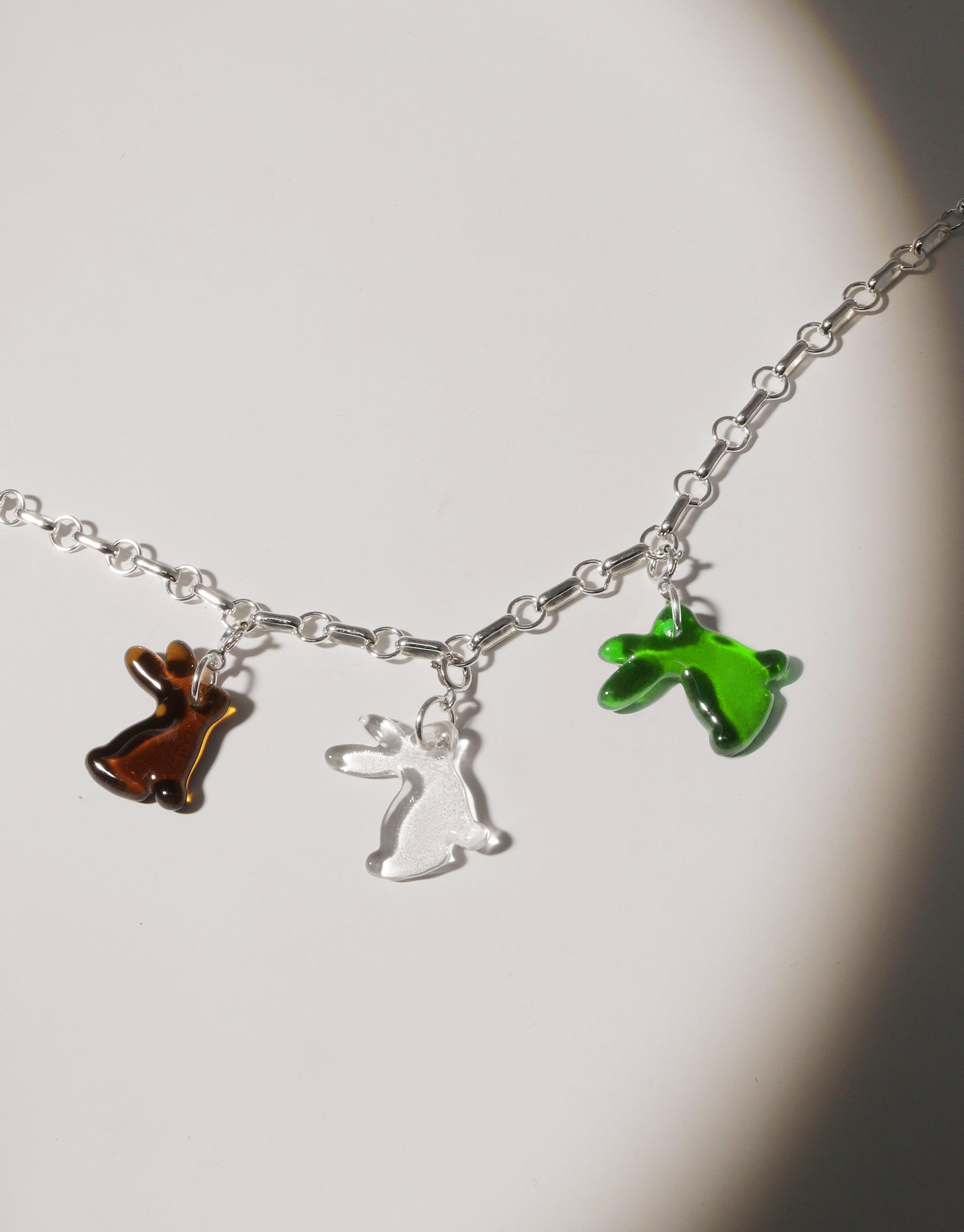 Silver chain necklace featuring three rabbit-shaped charms in brown, clear, and green glass, celebrating Lunar New Year. Handcrafted eco-friendly jewelry design for Rabbit Icon Charm by CLED