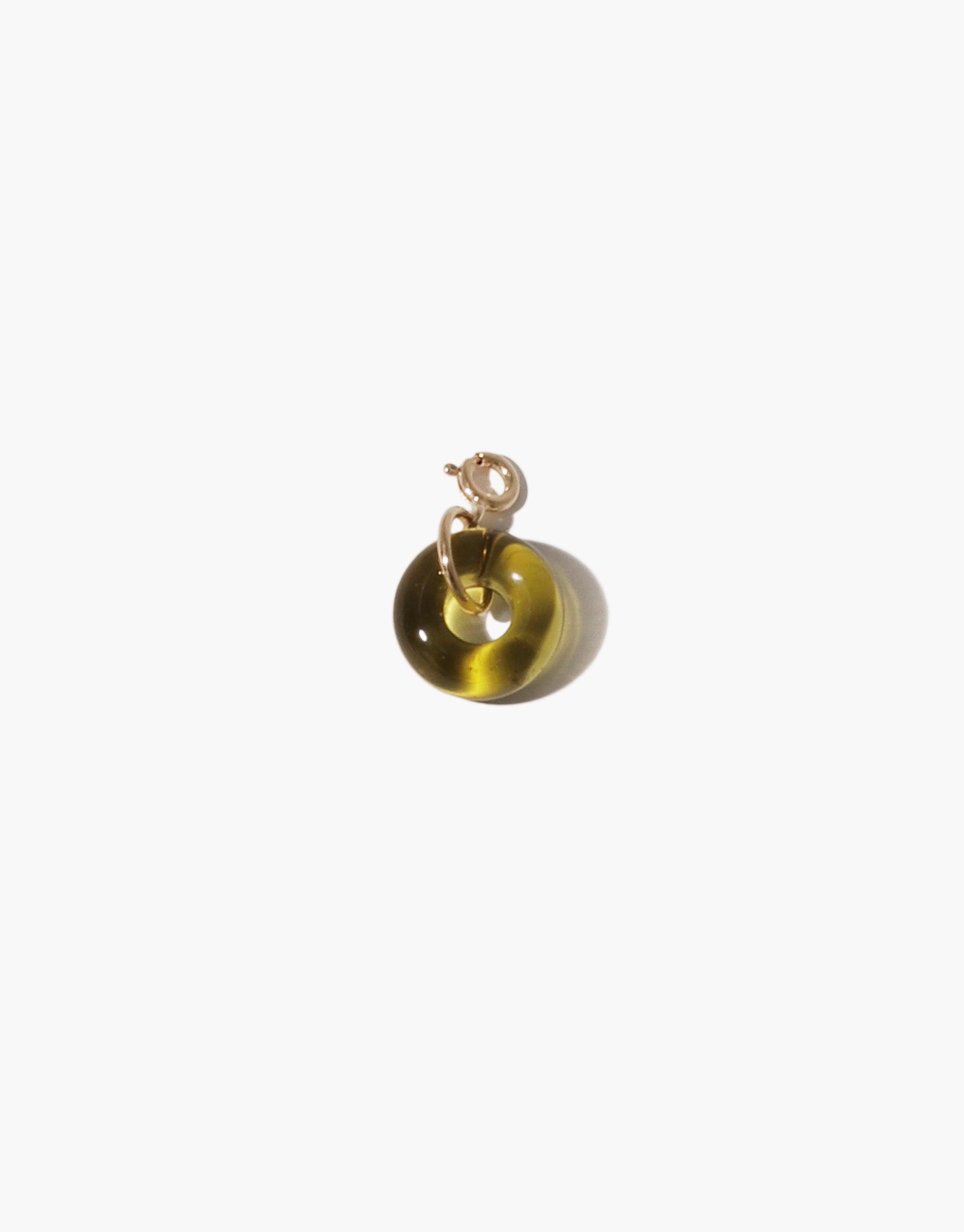 Donut-shaped charm in translucent amber glass with gold metal loop, showcasing upcycled eco-friendly materials. Versatile accessory for necklaces or bracelets, part of the Icon Charm collection. Handmade jewelry piece by CLED. Donut | Icon Charm.