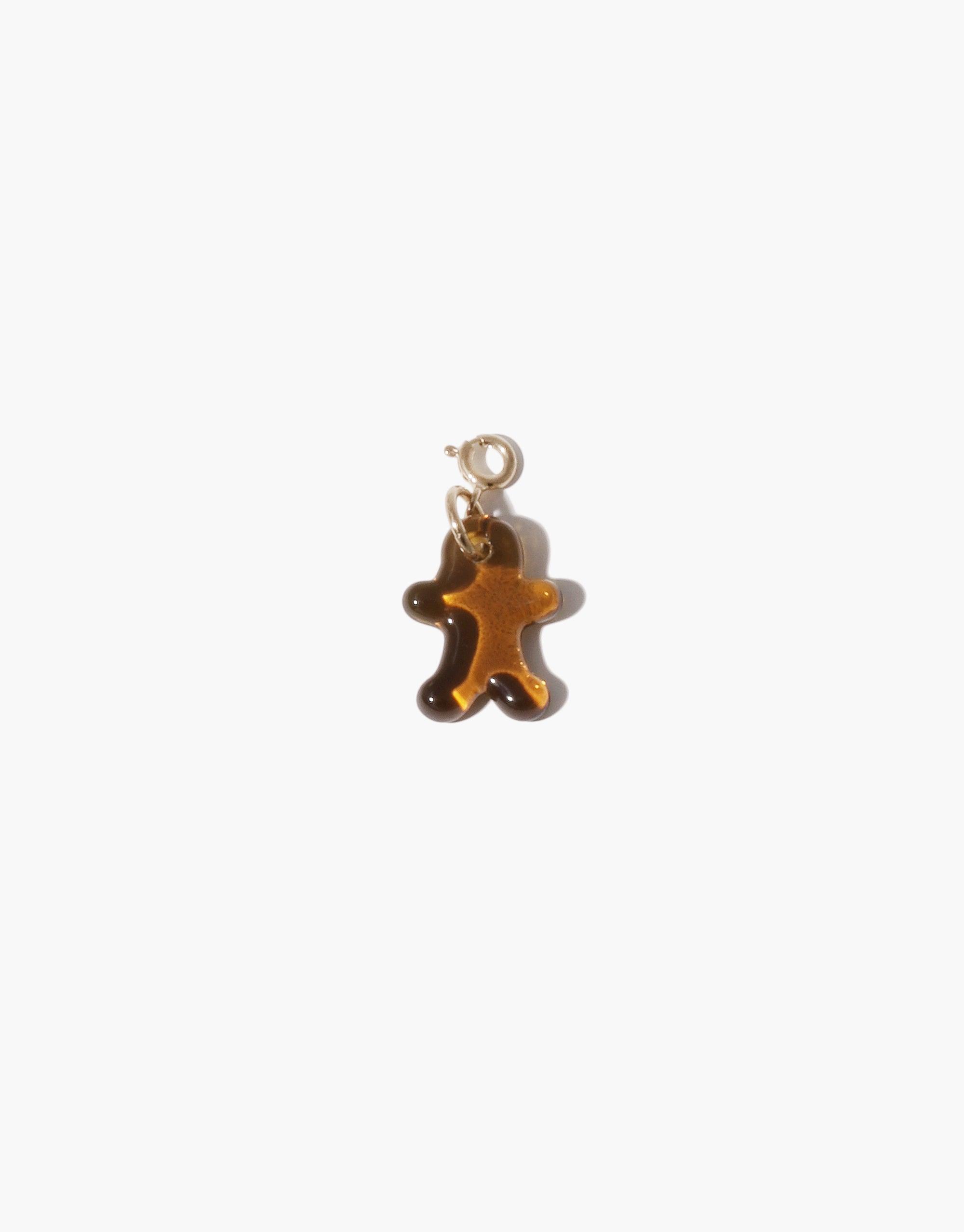 Ginger Man Icon Charm in amber-colored glass, shaped like a small figure with arms and legs outstretched. Gold-toned metal clasp for attachment to jewelry. Handcrafted charm from upcycled glass bottle, part of CLED's eco-friendly Icon Charm collection. Ginger Man | Icon Charm by CLED