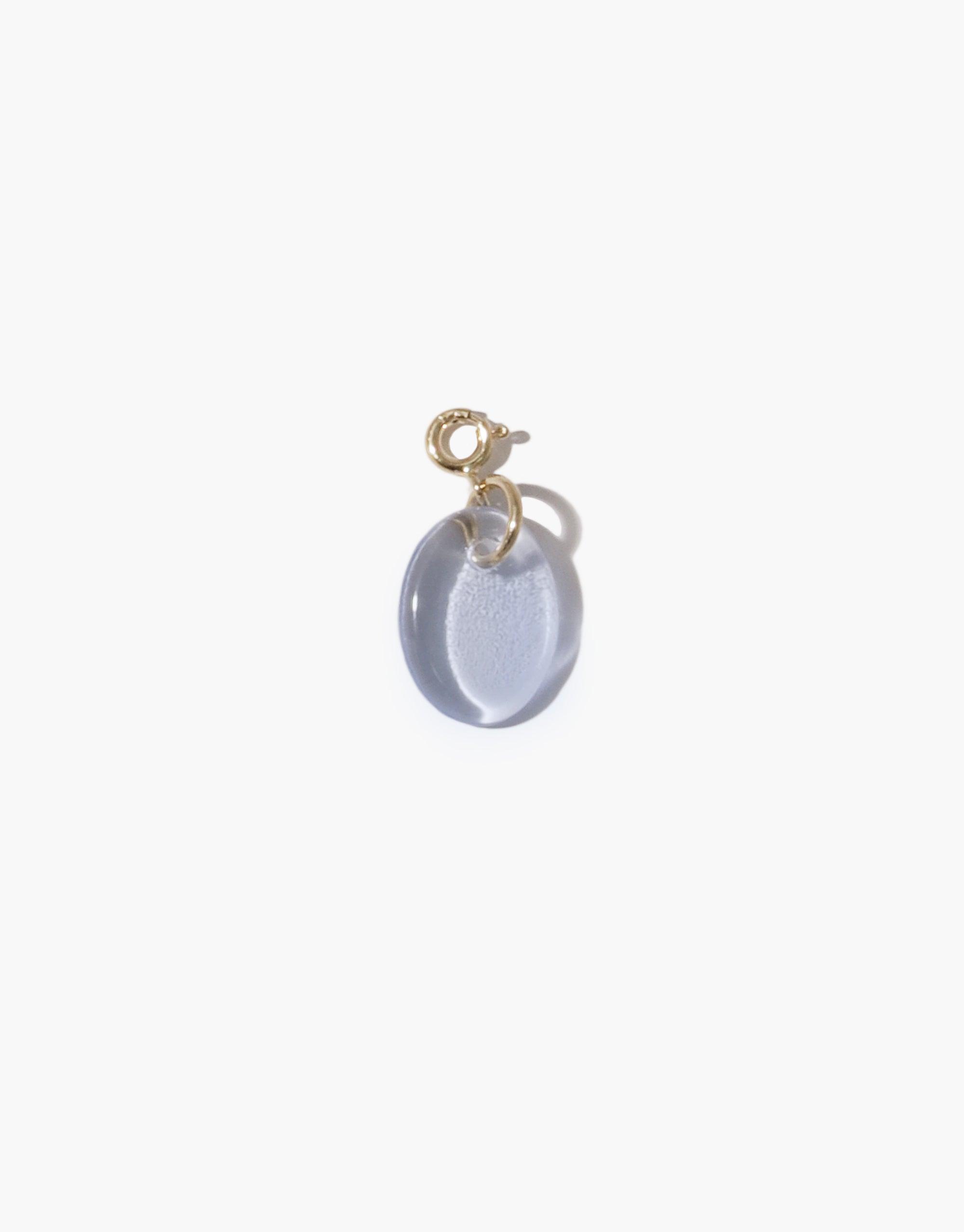 Oval Icon Charm featuring a translucent light blue glass pendant with gold-tone metal clasp, showcasing sustainable jewelry design. Versatile accessory for necklaces or bracelets, handcrafted from upcycled materials. Oval | Icon Charm by CLED