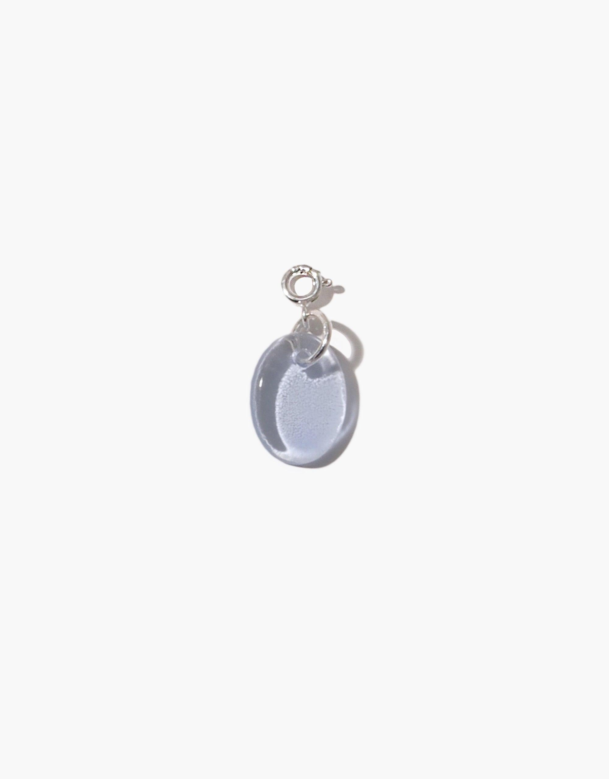 Oval Icon Charm featuring a translucent light blue glass pendant attached to a sterling silver loop. Handcrafted from upcycled eco-friendly materials. Versatile accessory for necklaces or bracelets. Sustainable jewelry piece by CLED. Oval | Icon Charm.