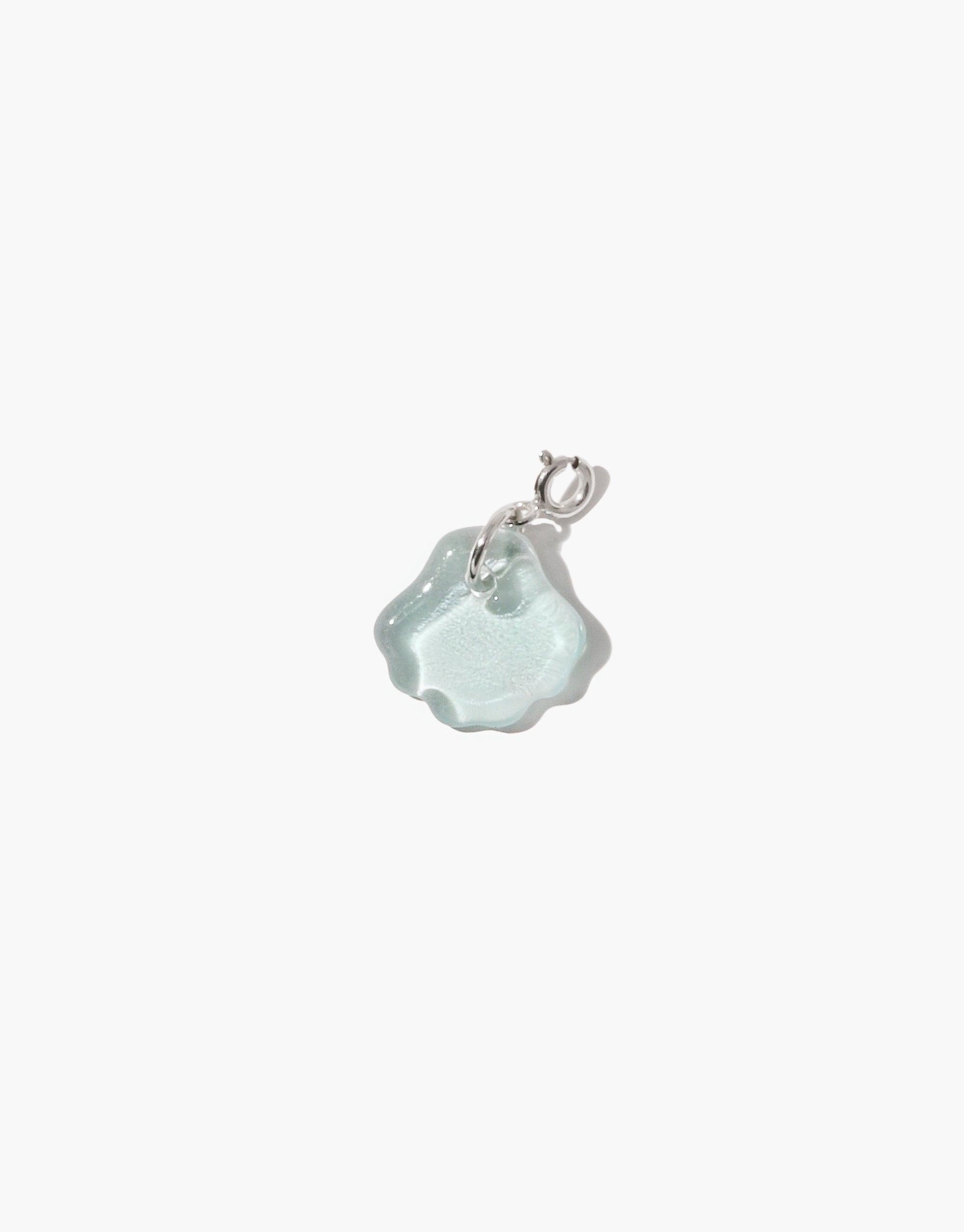 Shell-shaped charm in light blue upcycled glass with silver attachment, part of the Icon Charm collection. Handcrafted jewelry piece for necklaces or bracelets. Sustainable and eco-friendly accessory. Shell | Icon Charm by CLED.