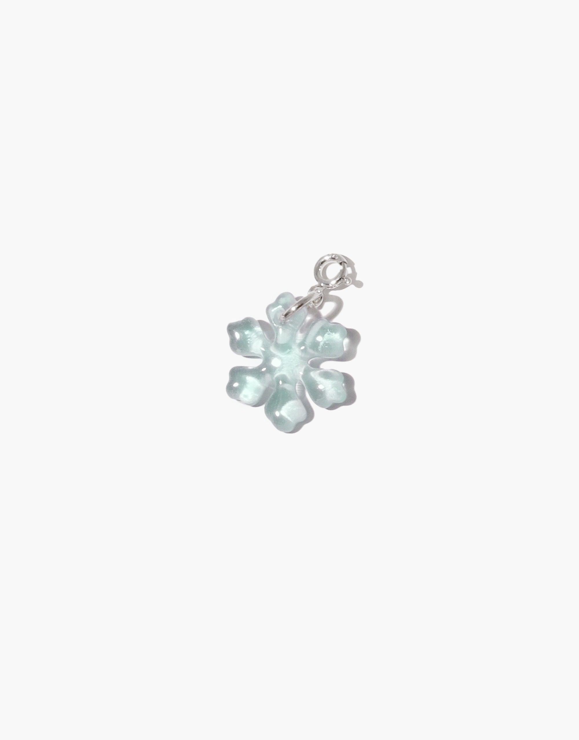 Delicate snowflake-shaped charm in pale blue upcycled glass with silver attachment, perfect for necklaces or bracelets. Handmade icon charm showcasing intricate details and sustainable craftsmanship. Snowflake | Icon Charm by CLED