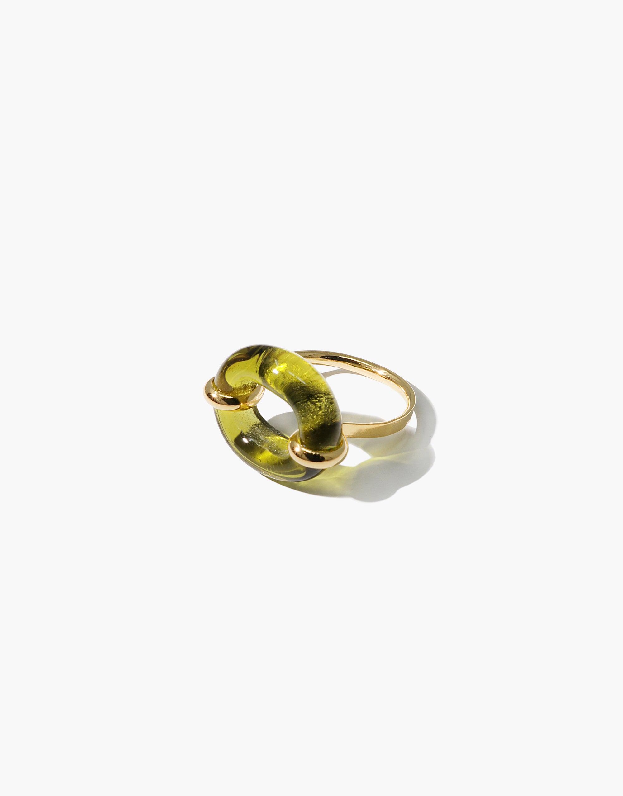 Elegant gold ring with translucent green circular centerpiece, symbolizing connection and sustainability. In The Loop Ring by CLED showcases unique design and craftsmanship.