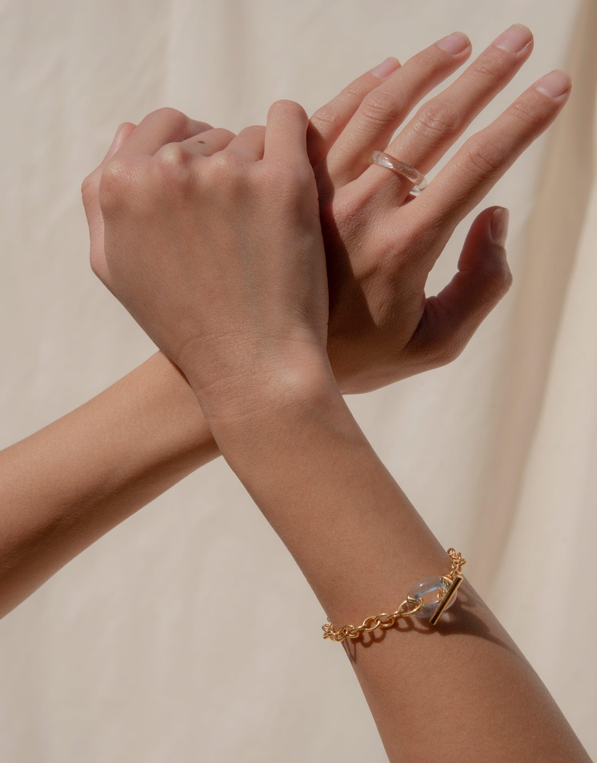 Elegant gold ITL Toggle Bracelet with eco gem accent on model's wrist, showcasing delicate chain design and toggle closure. Sustainable jewelry piece handcrafted from repurposed materials. CLED