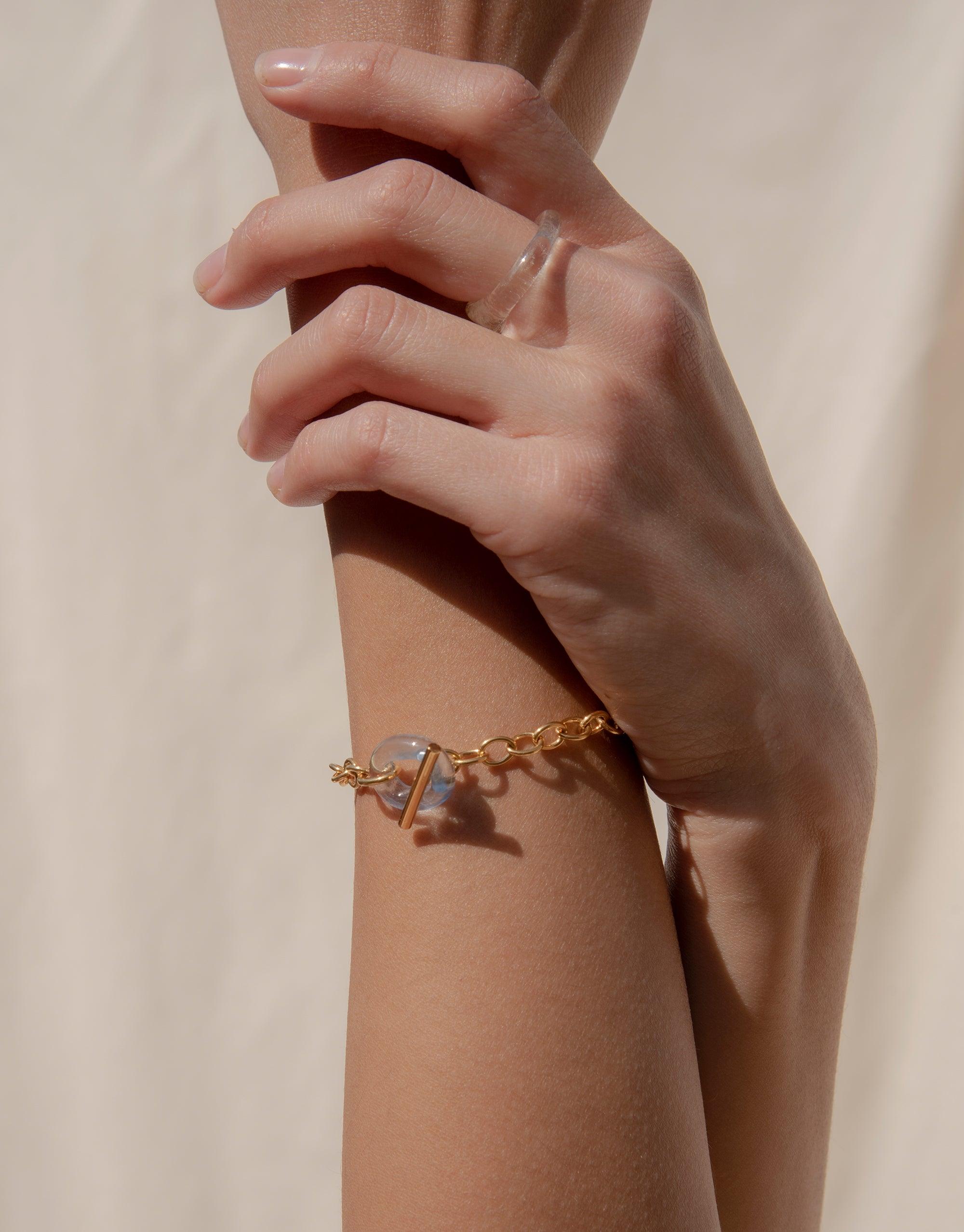 Elegant ITL Toggle Bracelet with interlocking gold links and small eco gem loop, worn on a person's wrist against a soft background. Lightweight and stylish accessory for everyday wear. Handcrafted sustainable jewelry by CLED.