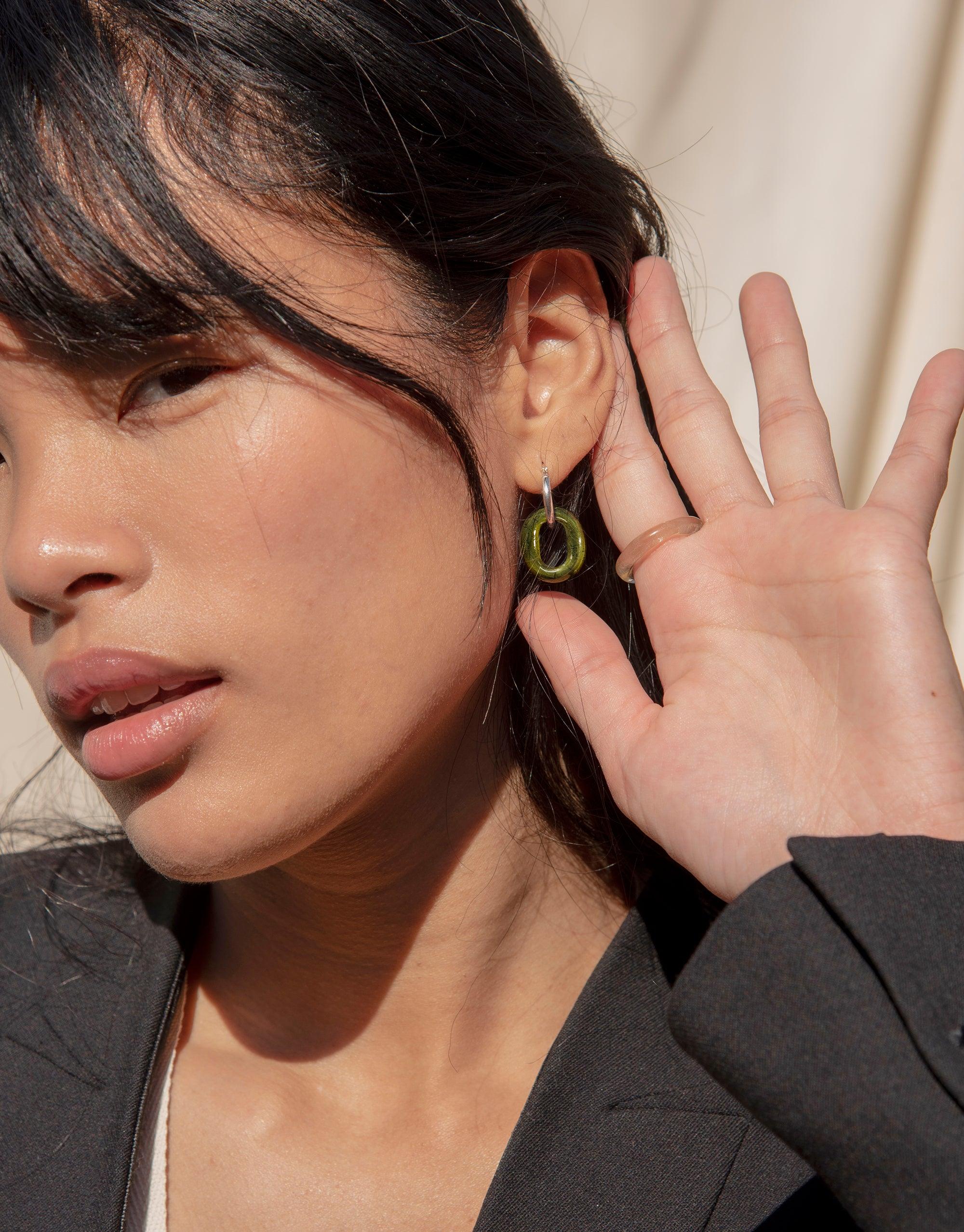 Elegant small hoop earrings featuring a distinctive green eco gem loop, showcasing sustainable jewelry design. Close-up view highlighting the unique texture and color of the repurposed glass. In The Loop Hoops | Small by CLED