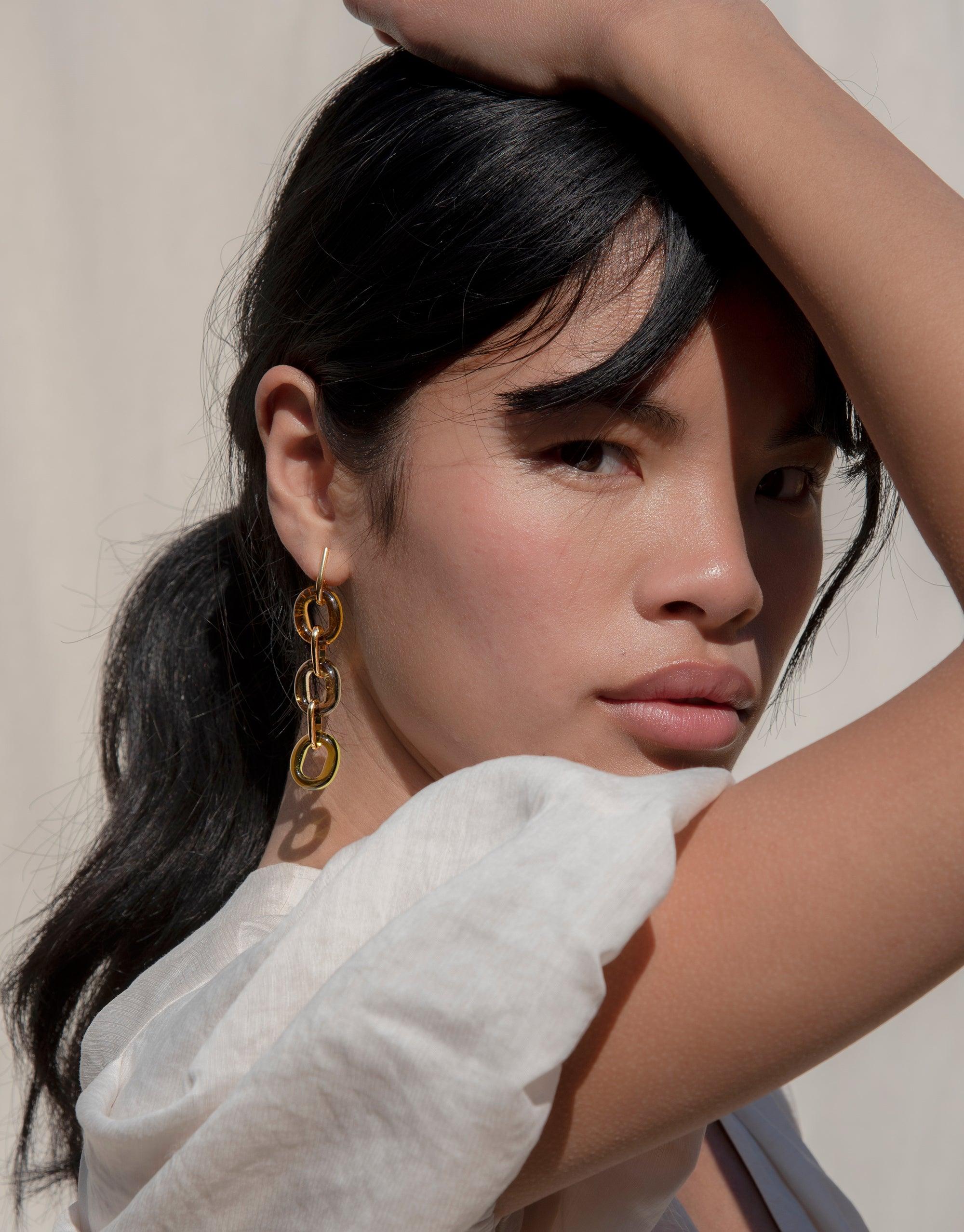 Stylish model wearing ITL Trio Earrings | Earth, featuring three golden loops cascading from ear. Eco-friendly design showcases repurposed glass, embodying sustainable luxury. Handcrafted in Los Angeles, perfect for the conscious fashion lover. CLED