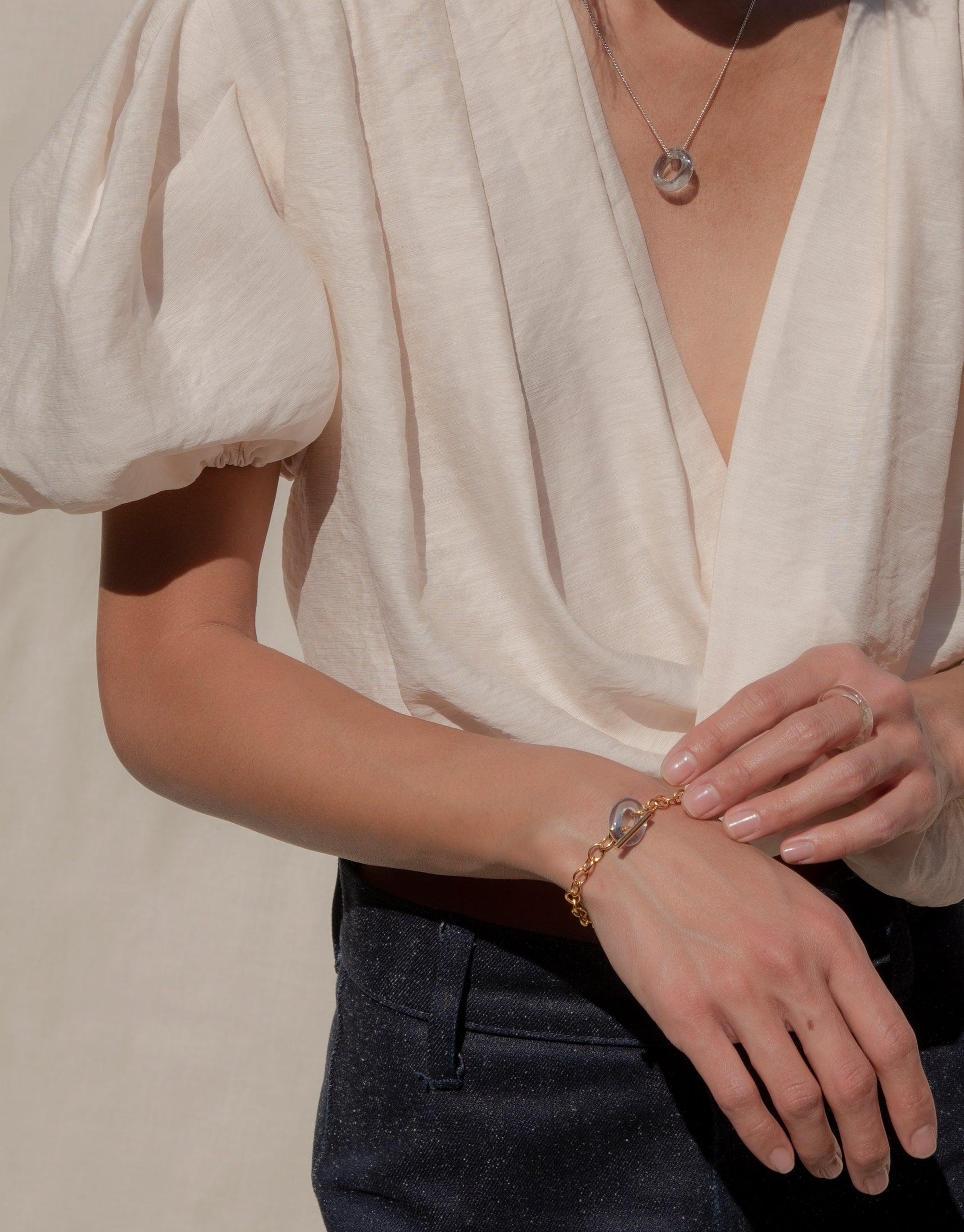 ITL Toggle Bracelet featuring lightweight interlocking links and eco gem, worn on wrist with white blouse. Elegant handcrafted jewelry piece showcasing sustainable design and versatile style. Perfect accessory for both casual and formal outfits. CLED