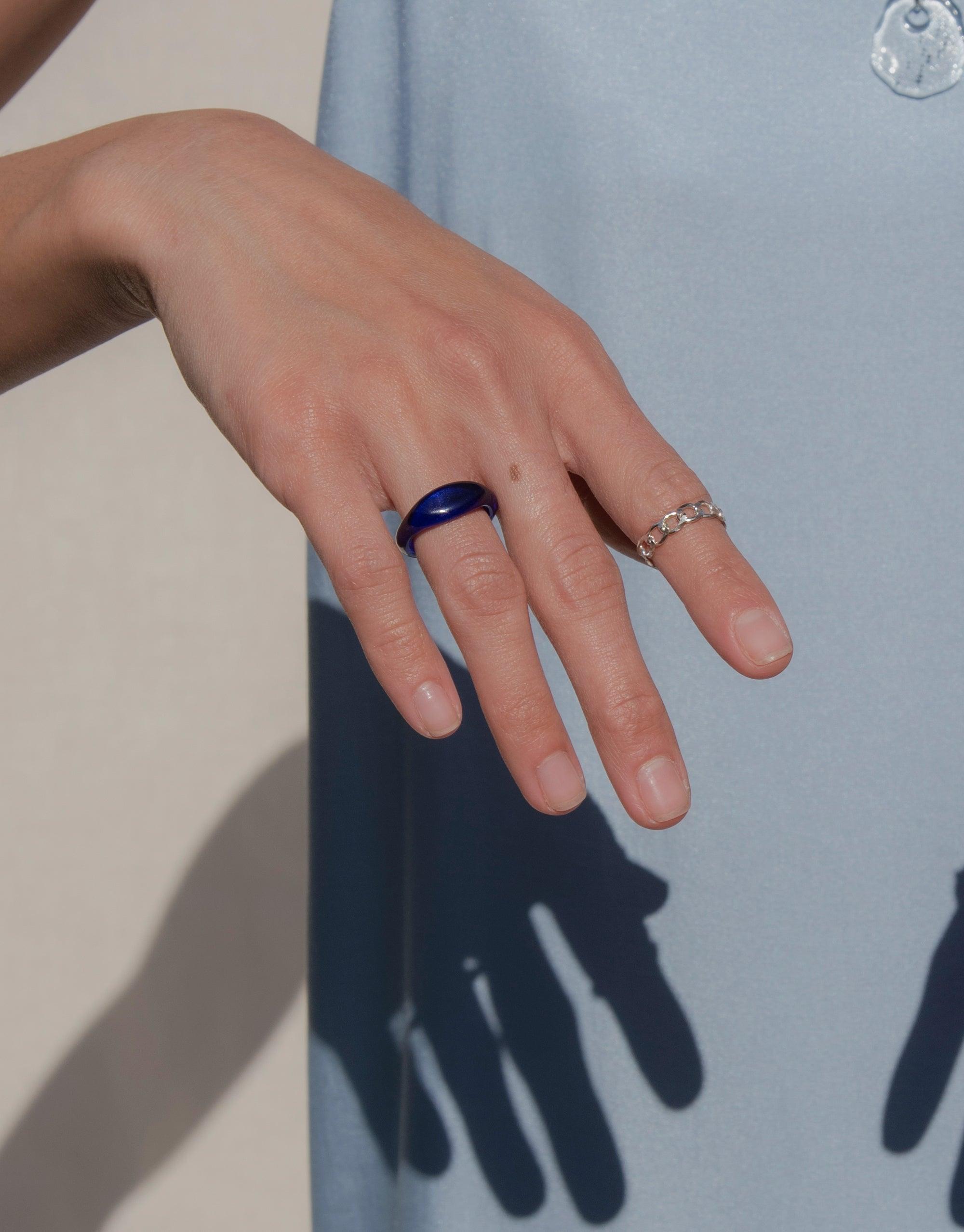Hand wearing blue Signet Ring Original from CLED's Messenger Collection, showcasing eco-friendly design and versatile styling. Paired with delicate band ring, highlighting the signet's bold color and unique shape. Sustainable jewelry by CLED.