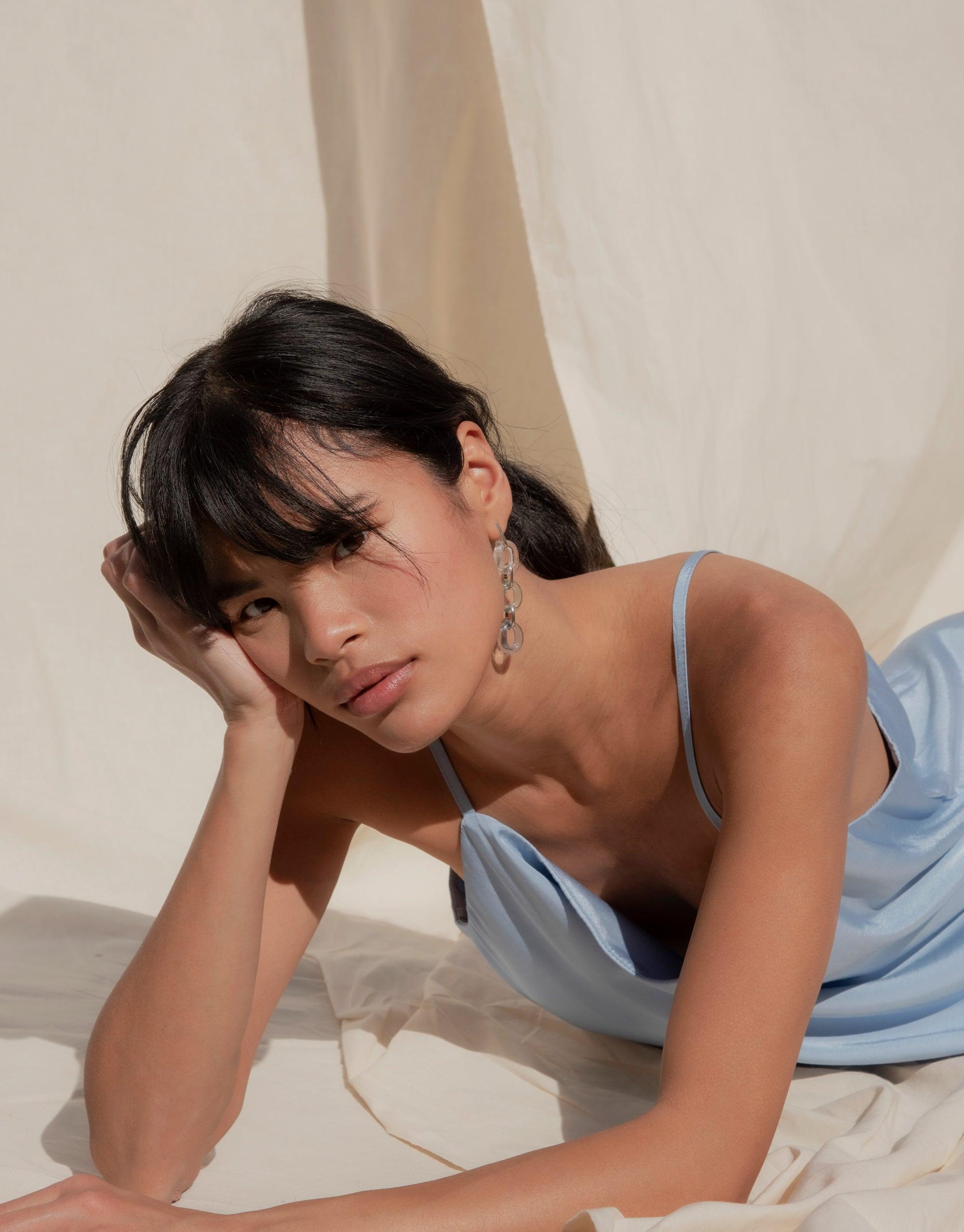 Elegant model wearing ITL Trio Earrings in Sky blue, featuring three cascading loops with eco-friendly glass accents. Soft lighting highlights the earrings' sparkle and length. Showcases CLED's sustainable jewelry design. ITL Trio Earrings | Sky.