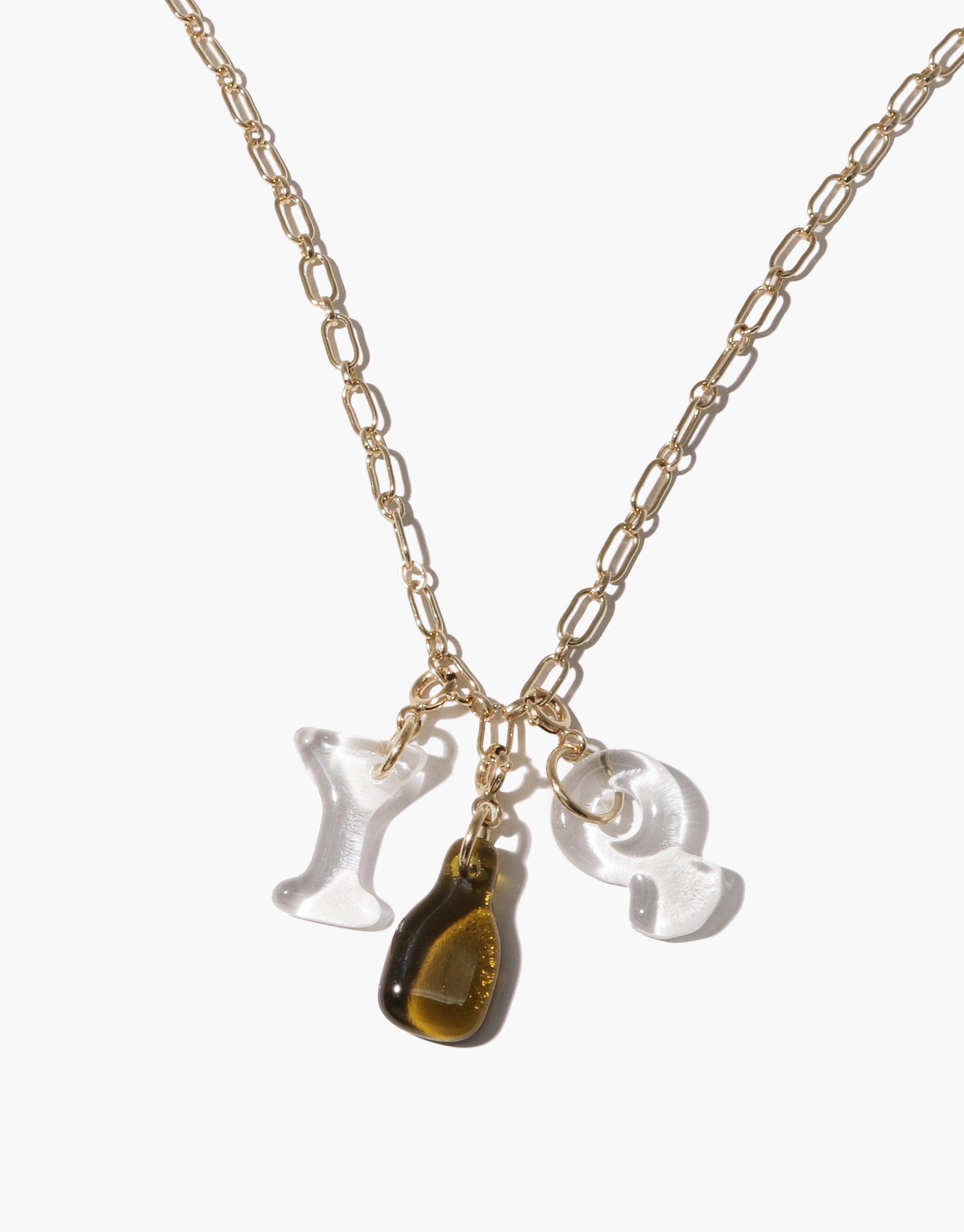 Gold chain necklace with three hanging charms: two clear glass shapes and one amber-colored bottle charm. Elegant and unique Bottle Icon Charm design for customizable jewelry. Handcrafted eco-friendly accessory by CLED.