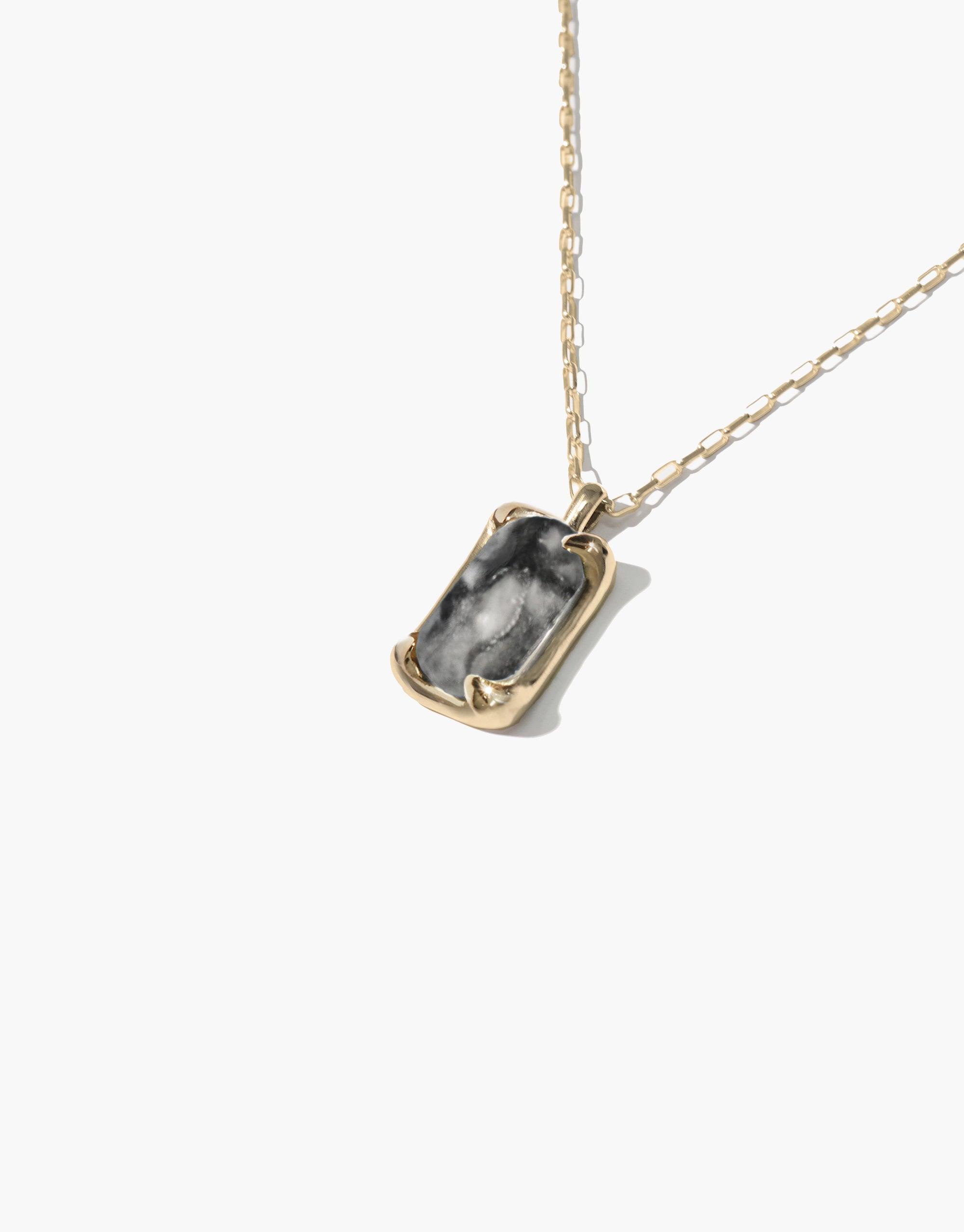 Prism Necklace | Marble featuring a unique rectangular pendant with swirling gray and white marble-like patterns, set in a gold-toned frame and suspended from a delicate gold chain. Handcrafted eco-friendly jewelry made from upcycled glass bottles. CLED