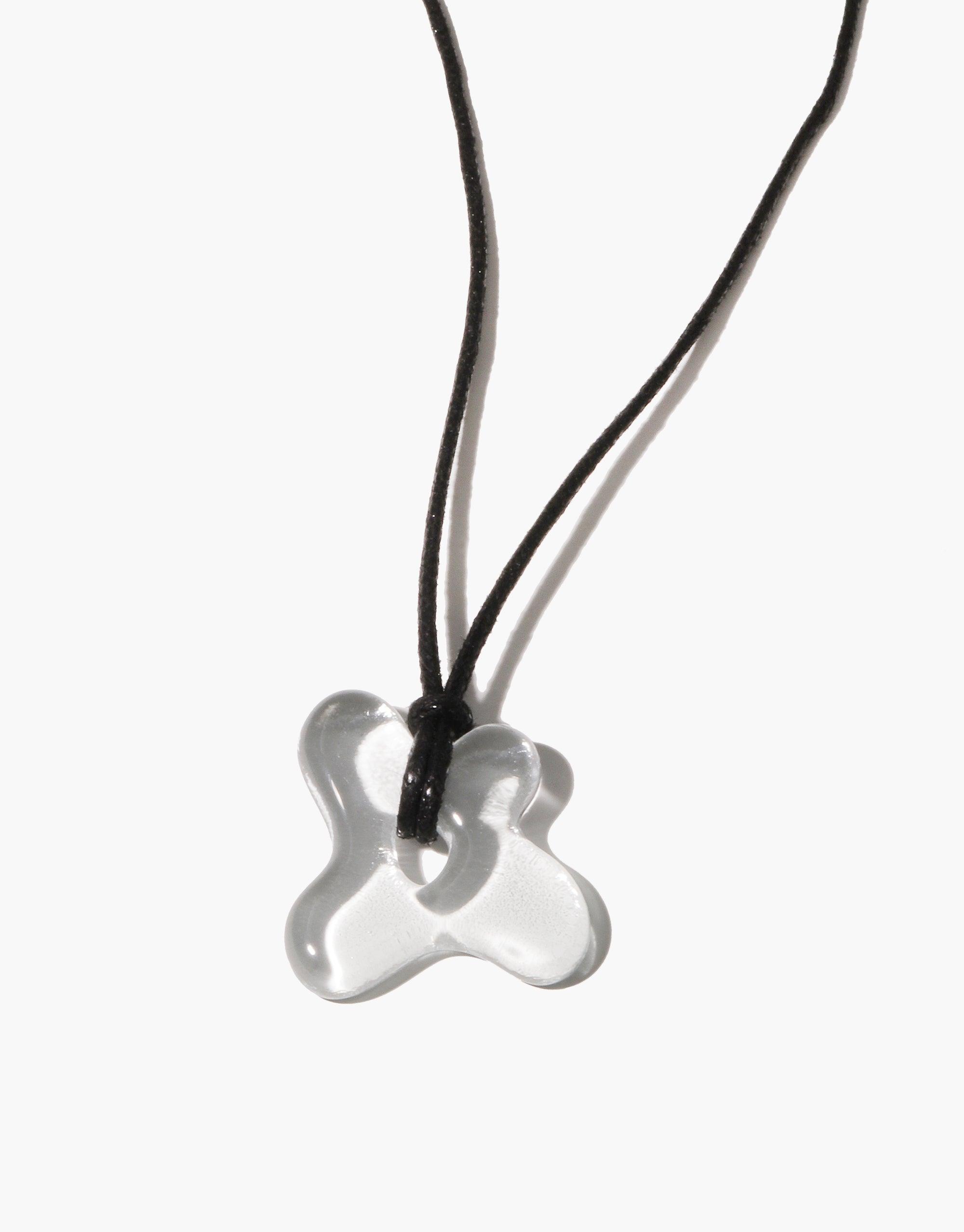 Sculptural Small Charm Necklace featuring a transparent glass pendant in an organic shape, suspended on a black cotton cord. Handcrafted eco-friendly jewelry made from upcycled window glass. Unique, sustainable accessory by CLED. Sculptural Small Charm Necklace | C.